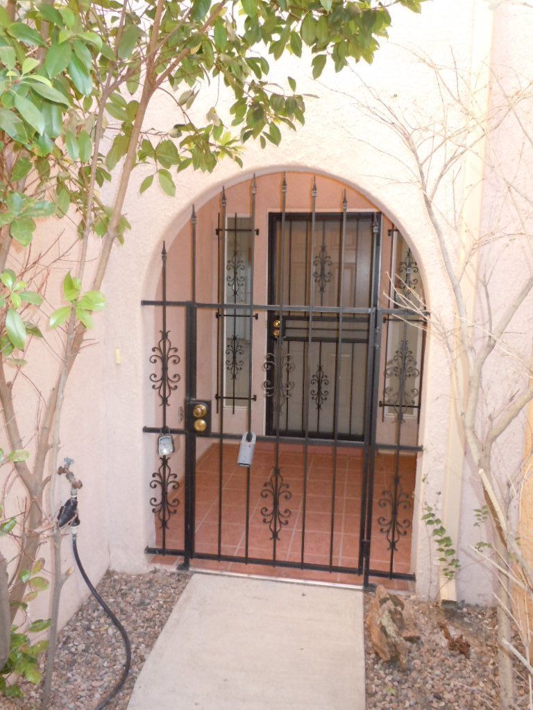 A wrought iron gate surrounds the entrance to a house