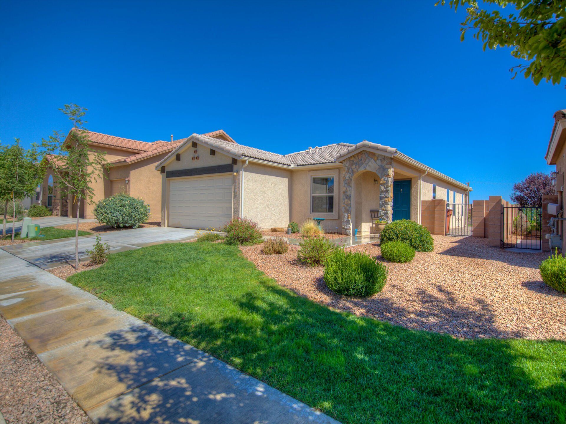 A house with a lush green lawn and a blue sky in the background