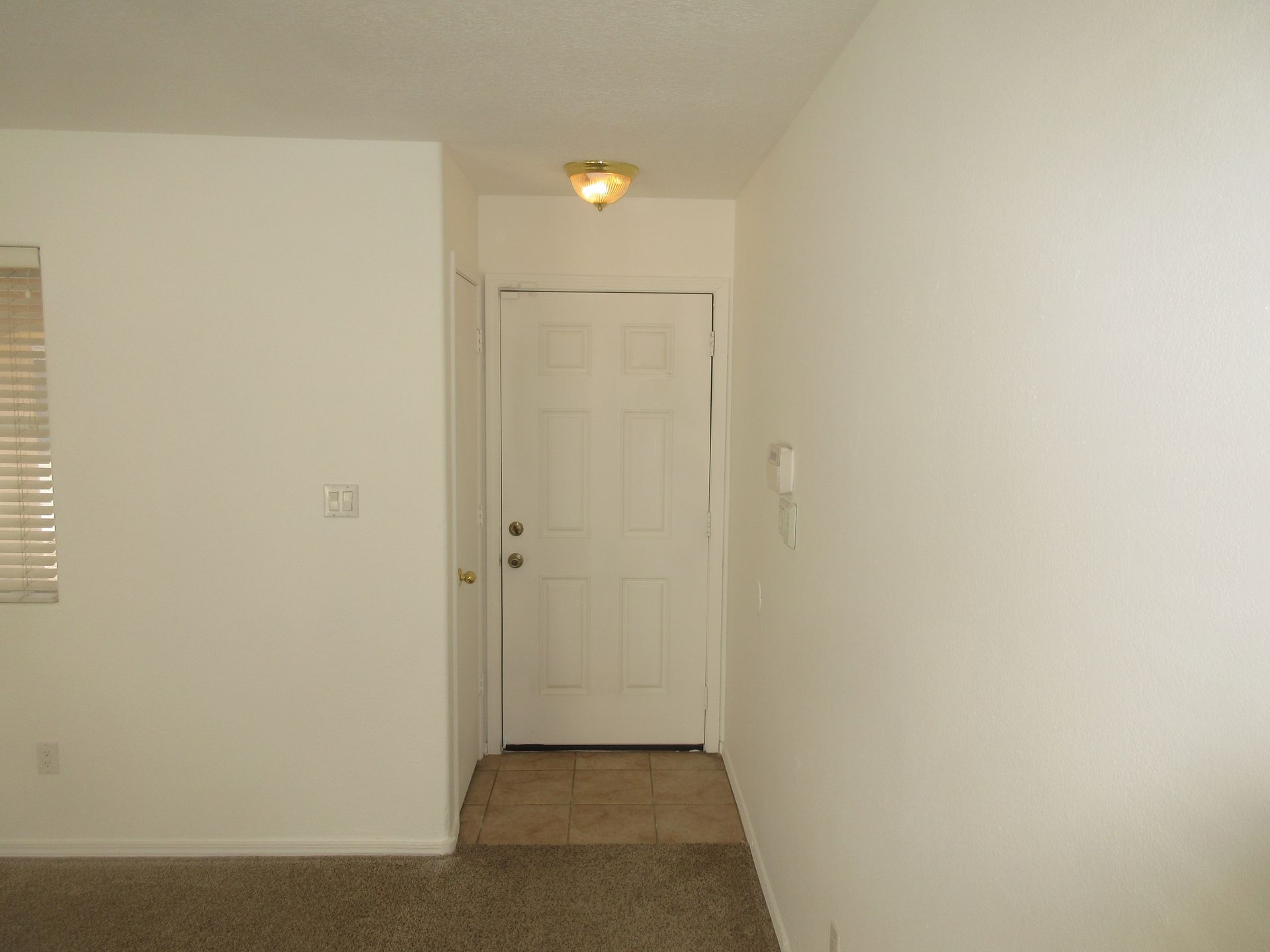 An empty hallway with a door and a window in a house.