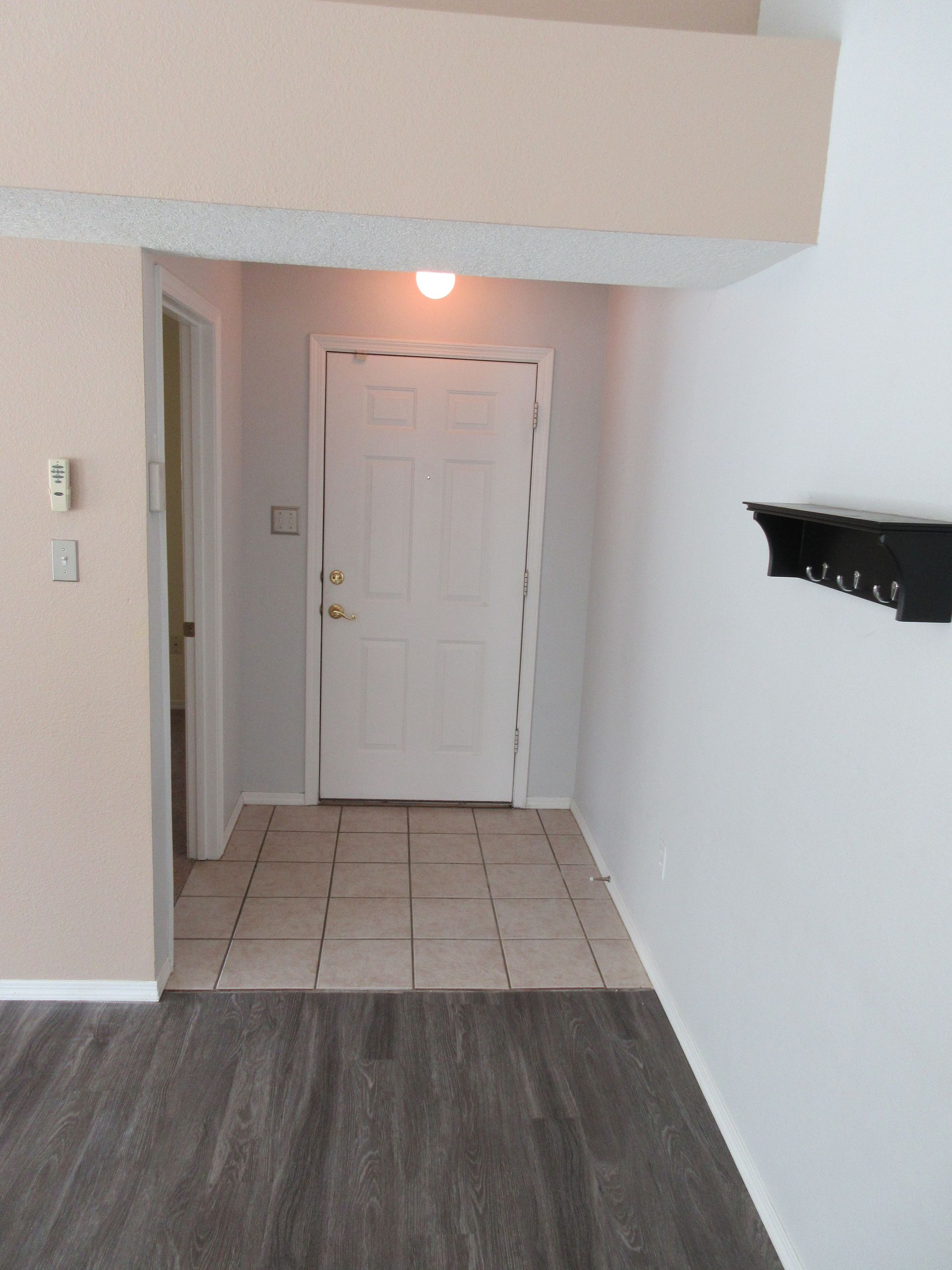 An empty hallway with a door and a shelf on the wall