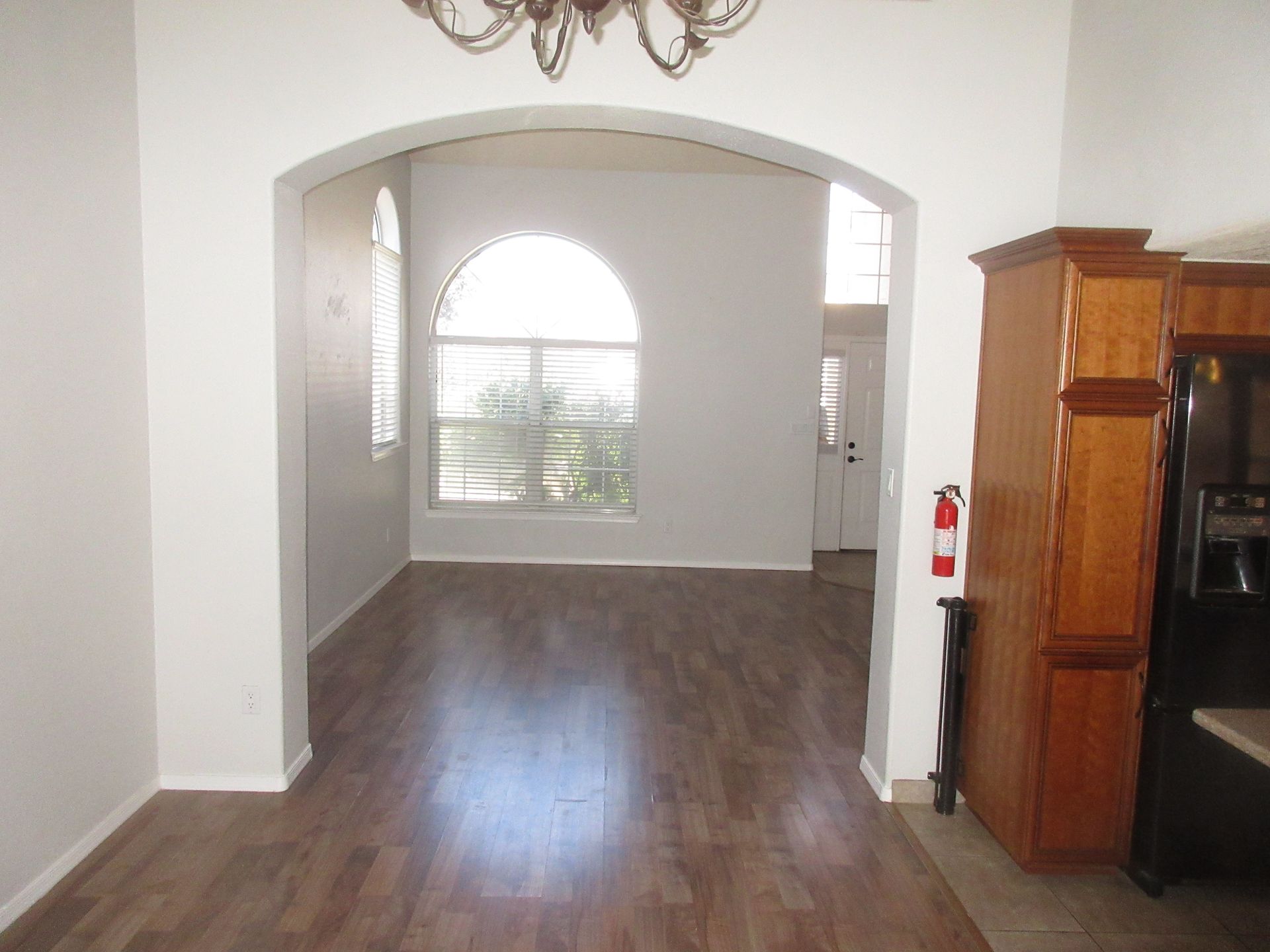 An empty living room with hardwood floors and white walls