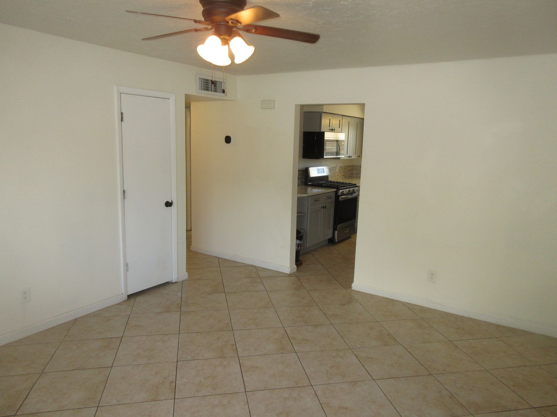 An empty room with a ceiling fan in the corner