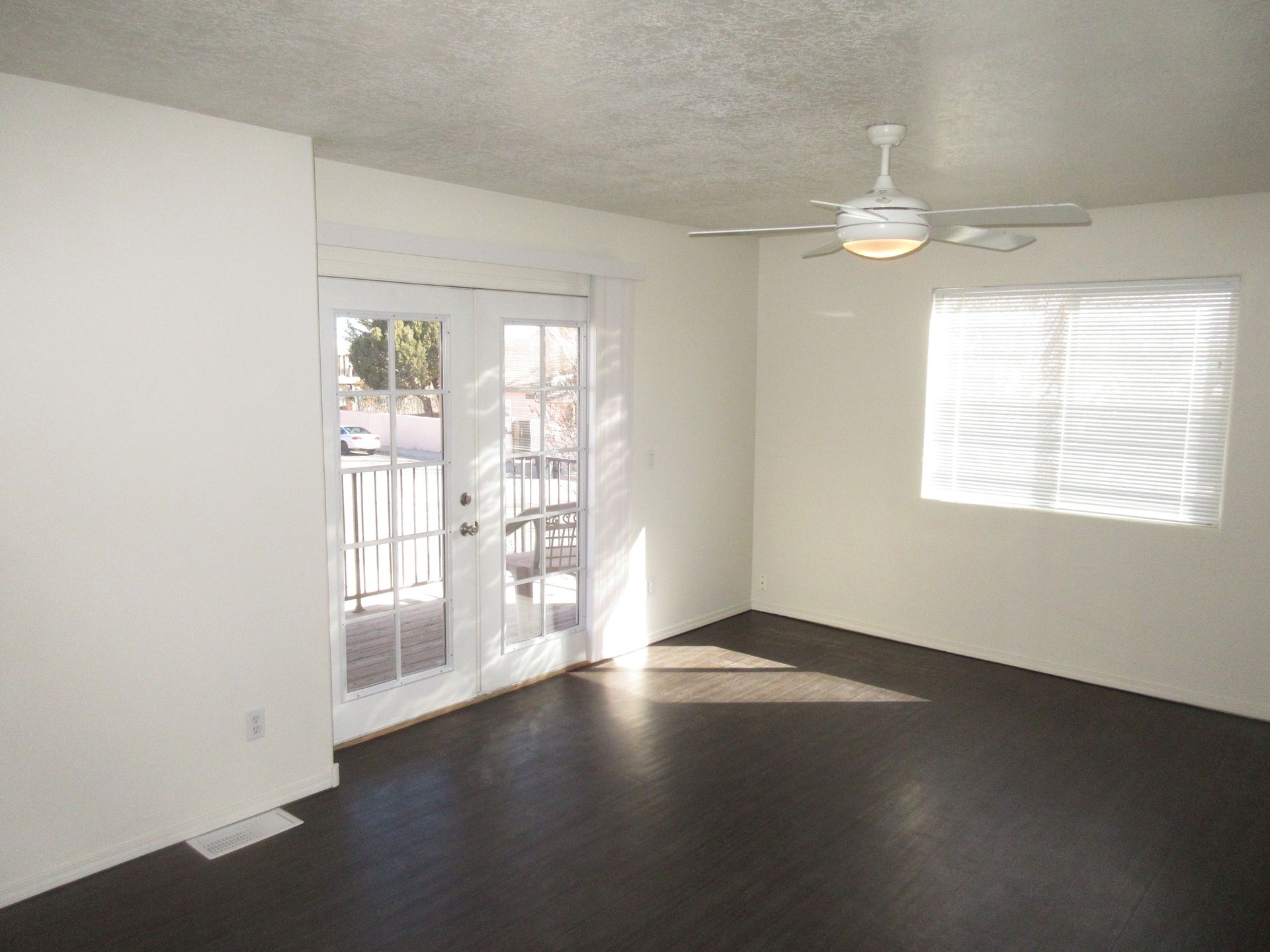 An empty living room with a ceiling fan and sliding glass doors