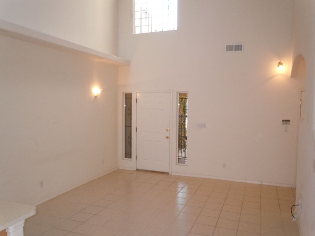 An empty living room with white walls and tile floors.