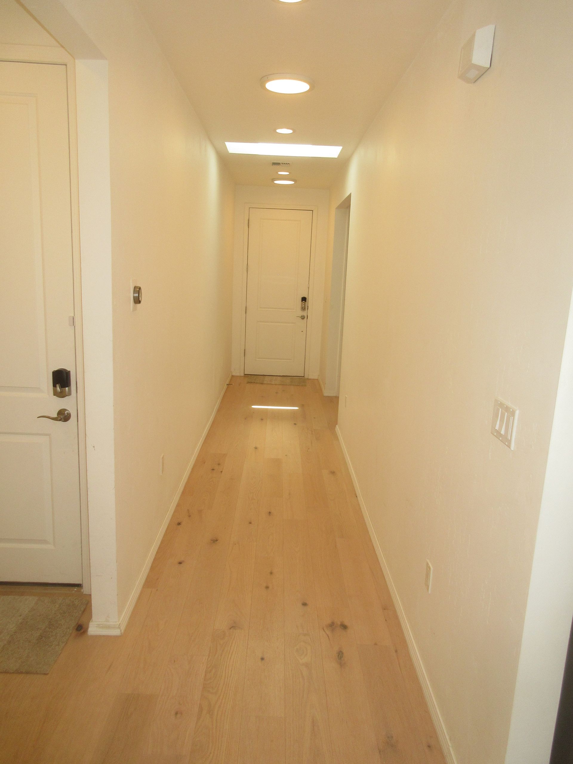 A long hallway with wooden floors and white walls