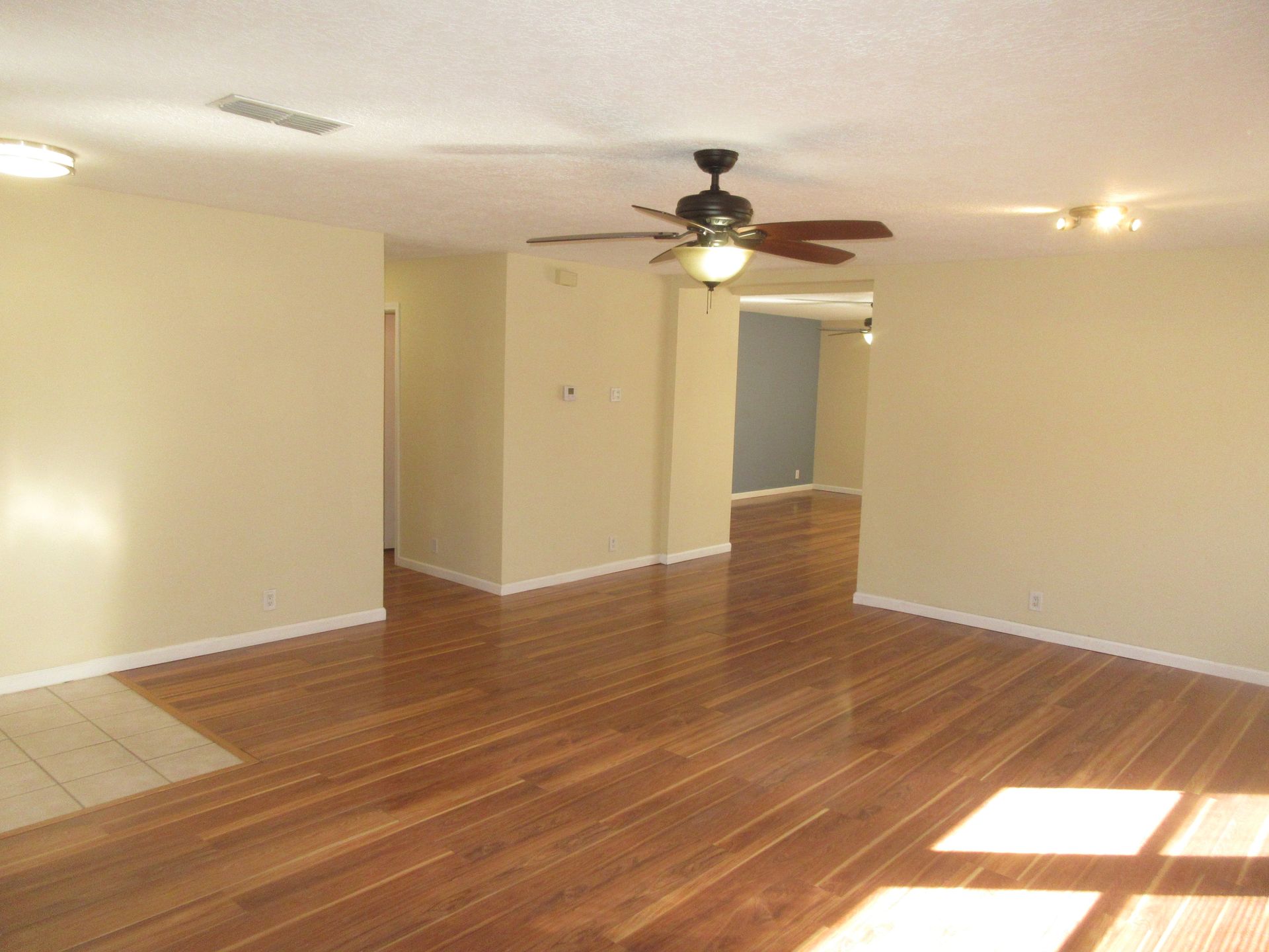 An empty living room with hardwood floors and a ceiling fan