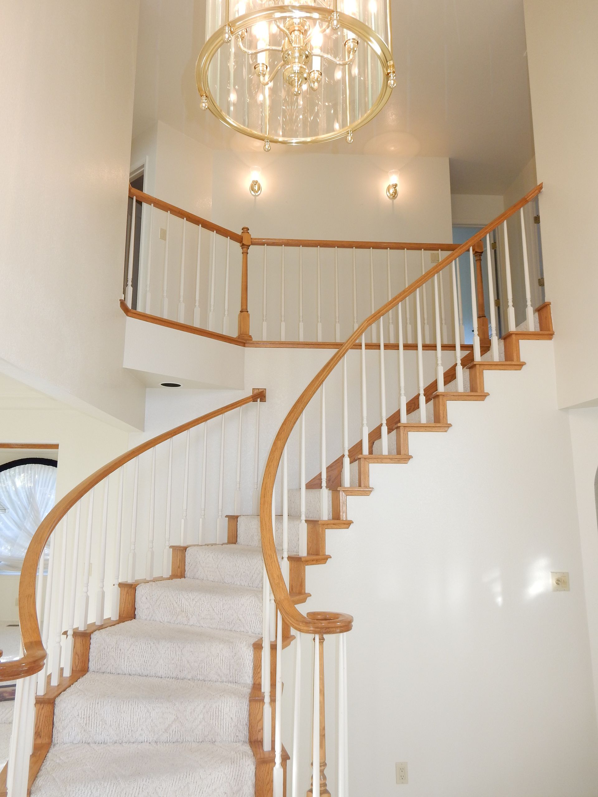 A curved staircase with a chandelier hanging from the ceiling