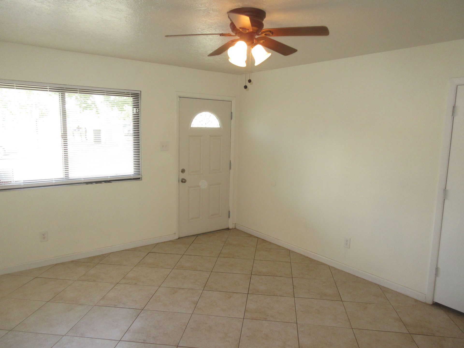 An empty room with a ceiling fan and a door