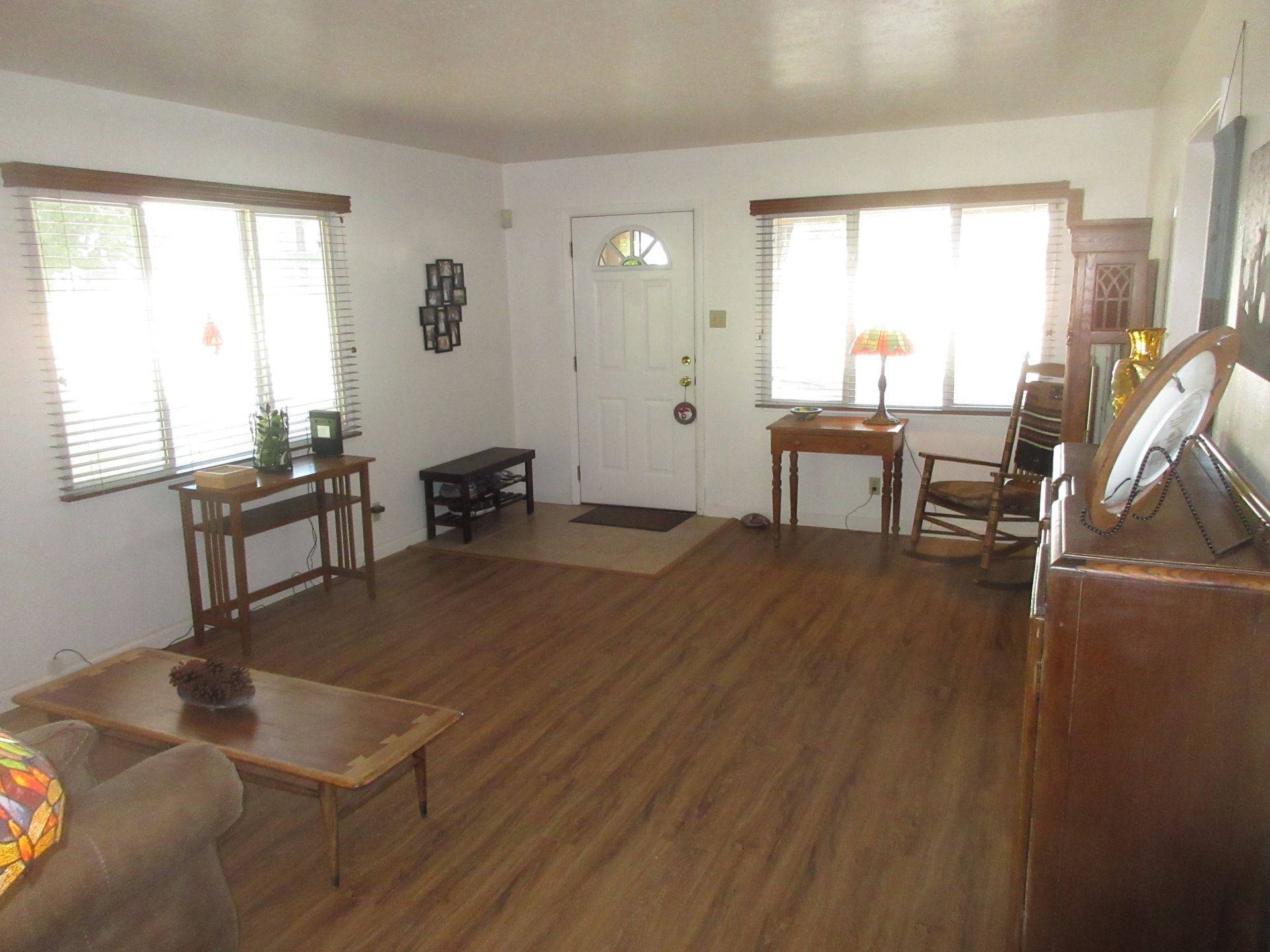 A living room with hardwood floors , a couch , a table , and a rocking chair.