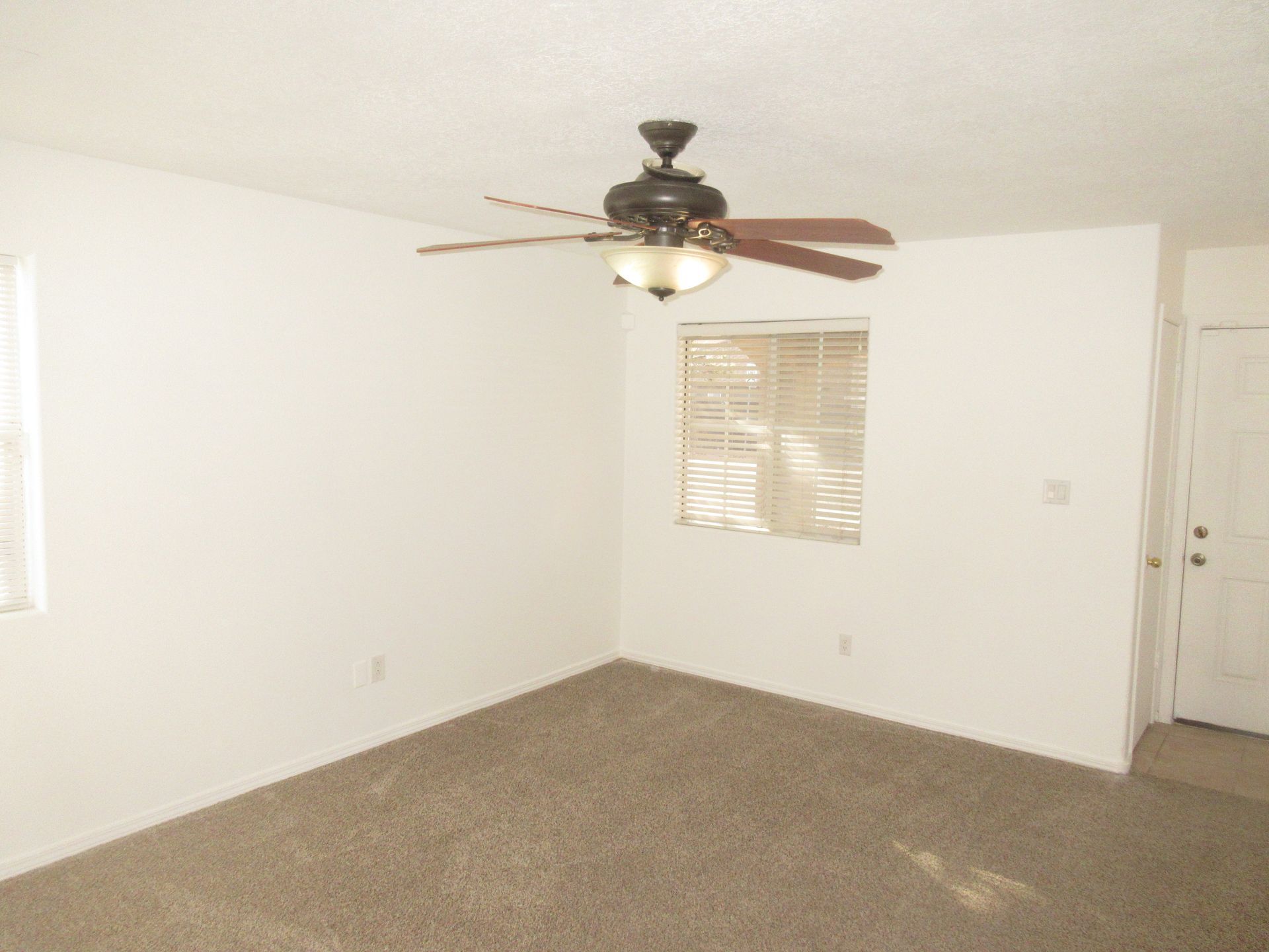 An empty room with a ceiling fan and a window