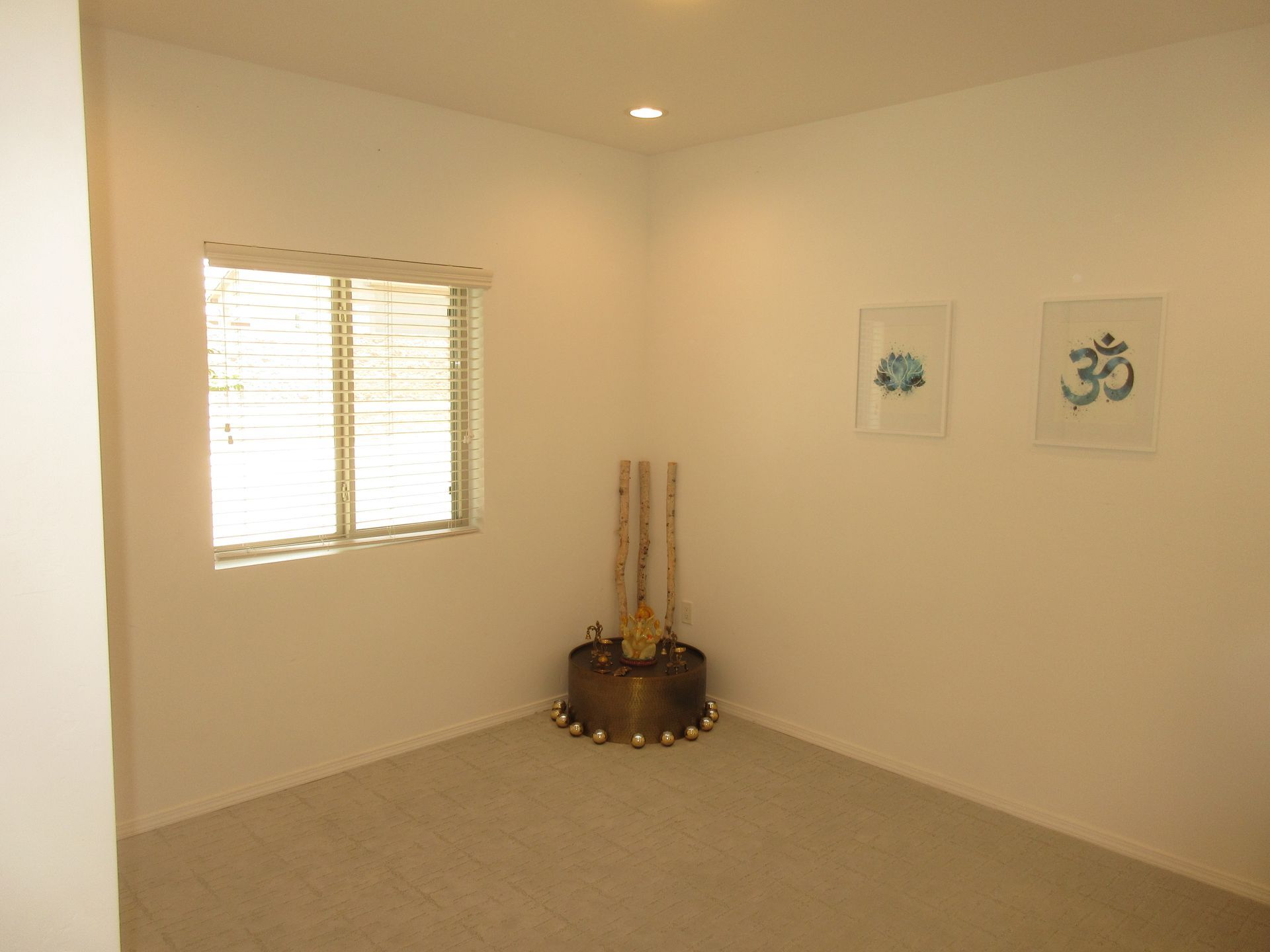 A room with white walls , a window , and a drum in the corner.