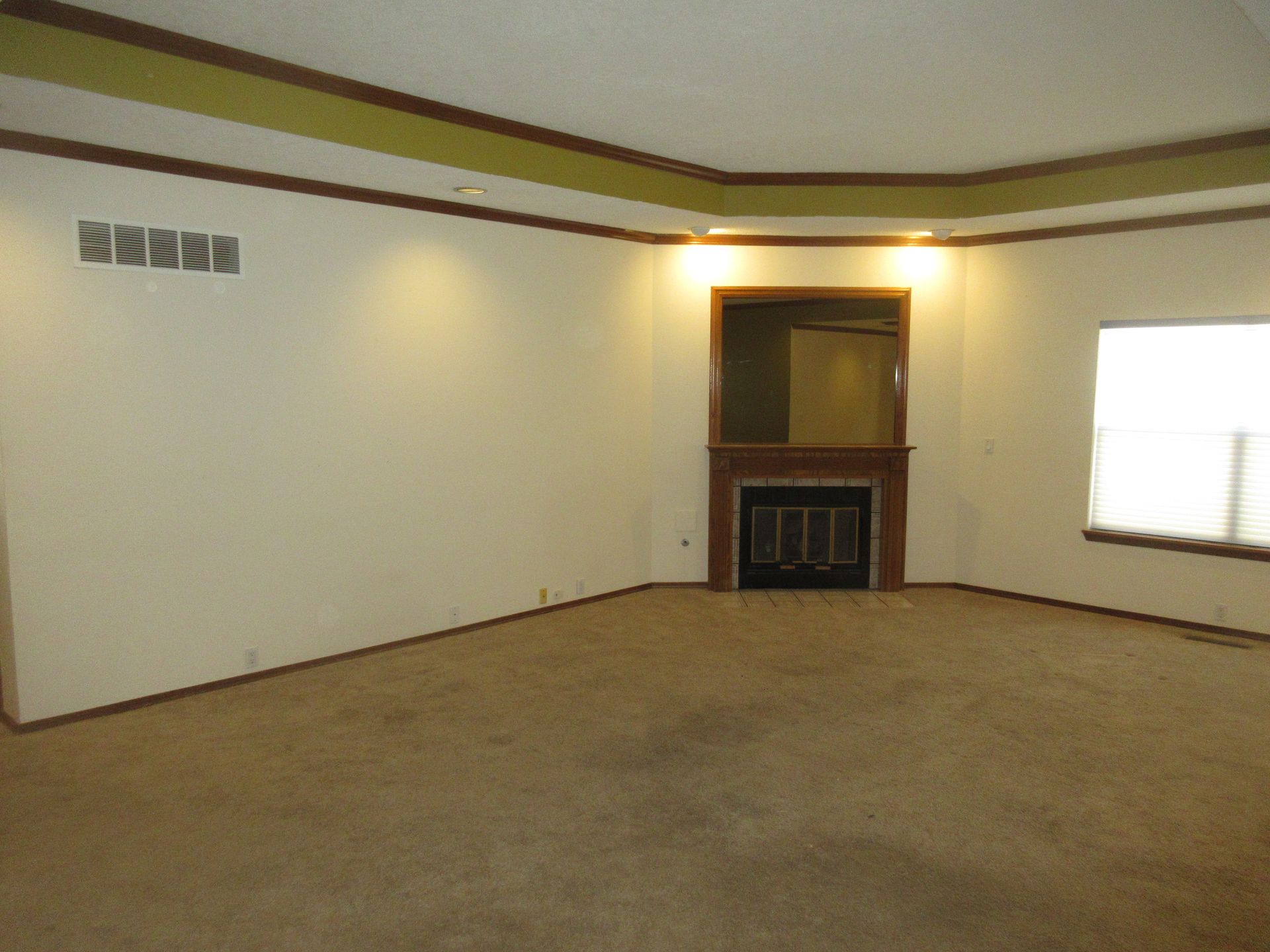 An empty living room with a fireplace and a window