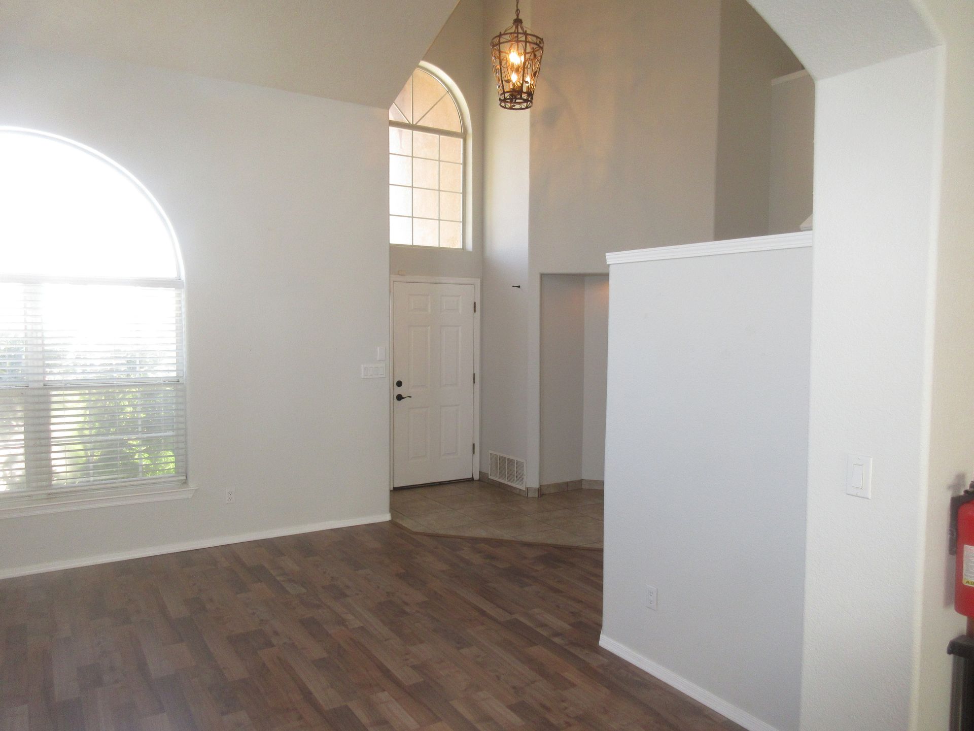 An empty living room with hardwood floors and a large window.