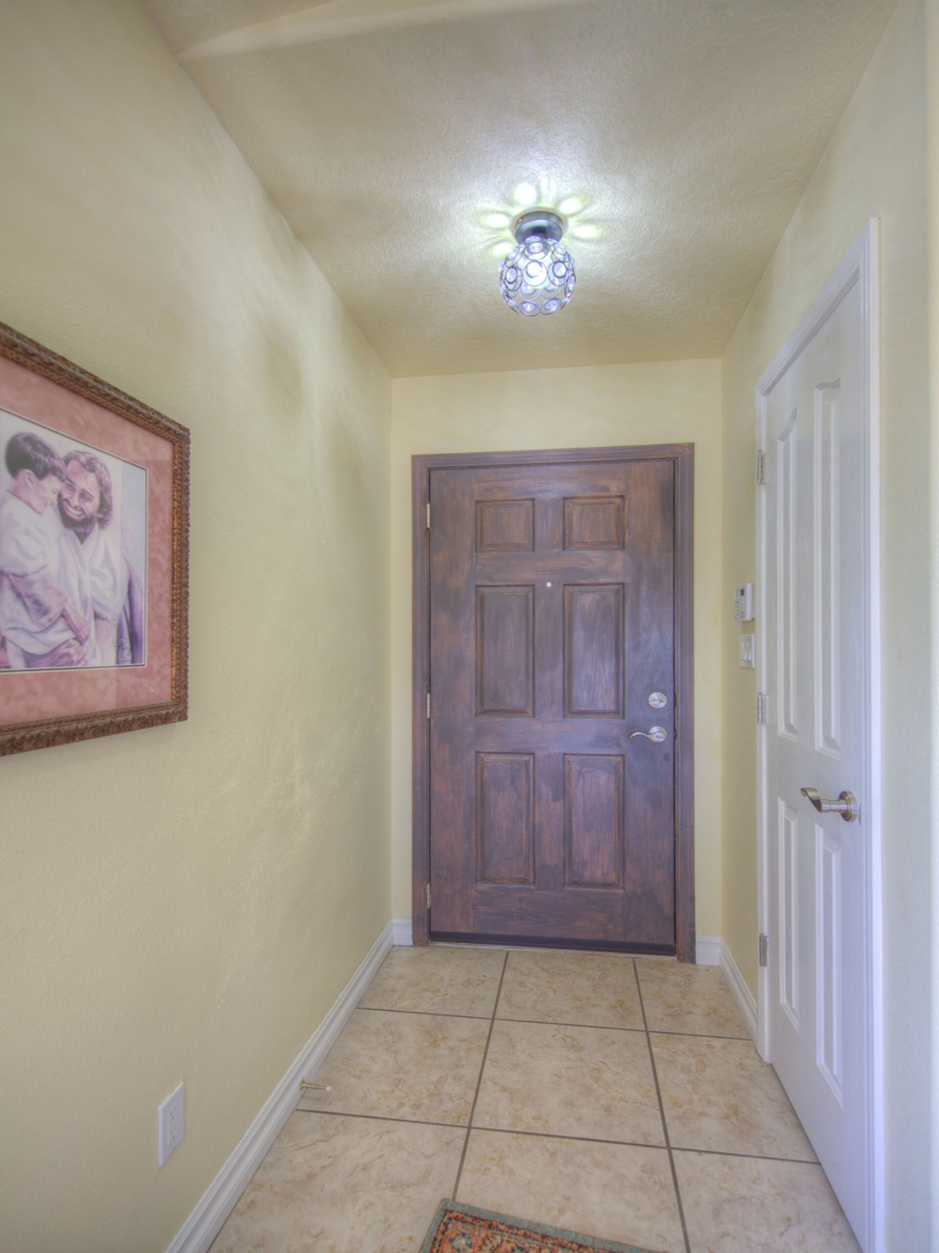 A hallway with a wooden door and a picture on the wall.