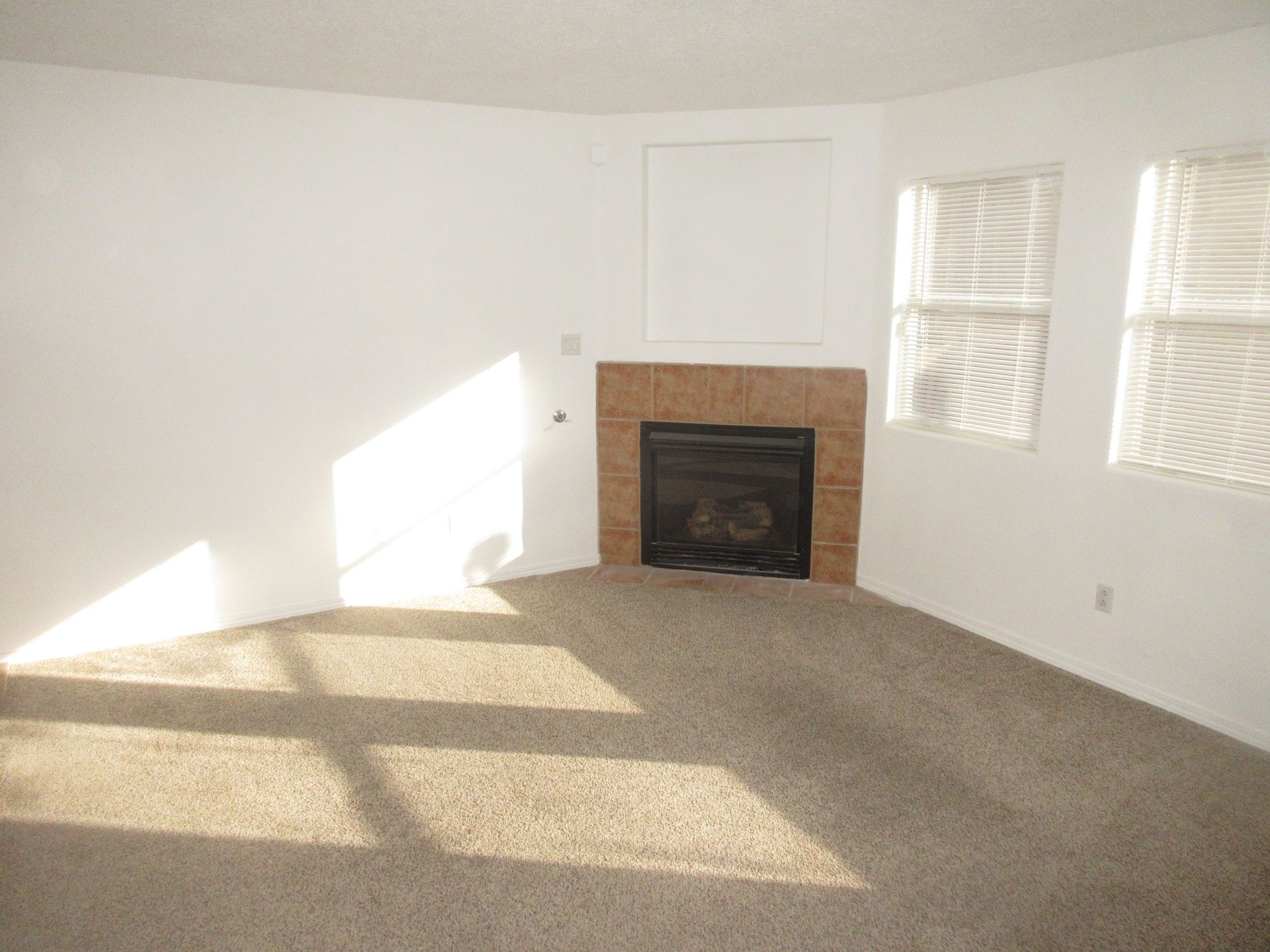 An empty living room with a fireplace in the corner
