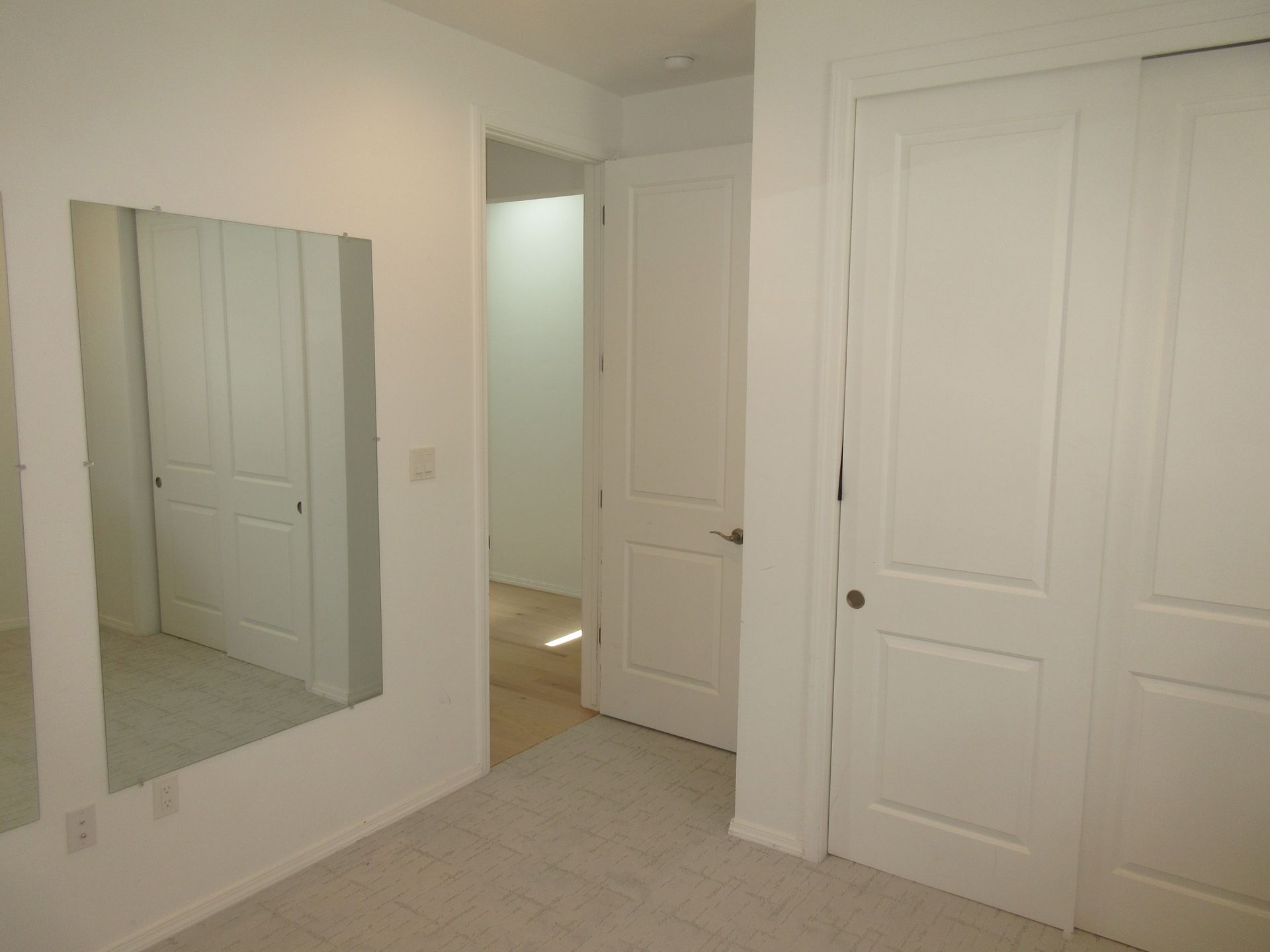 An empty bedroom with a large mirror on the wall.