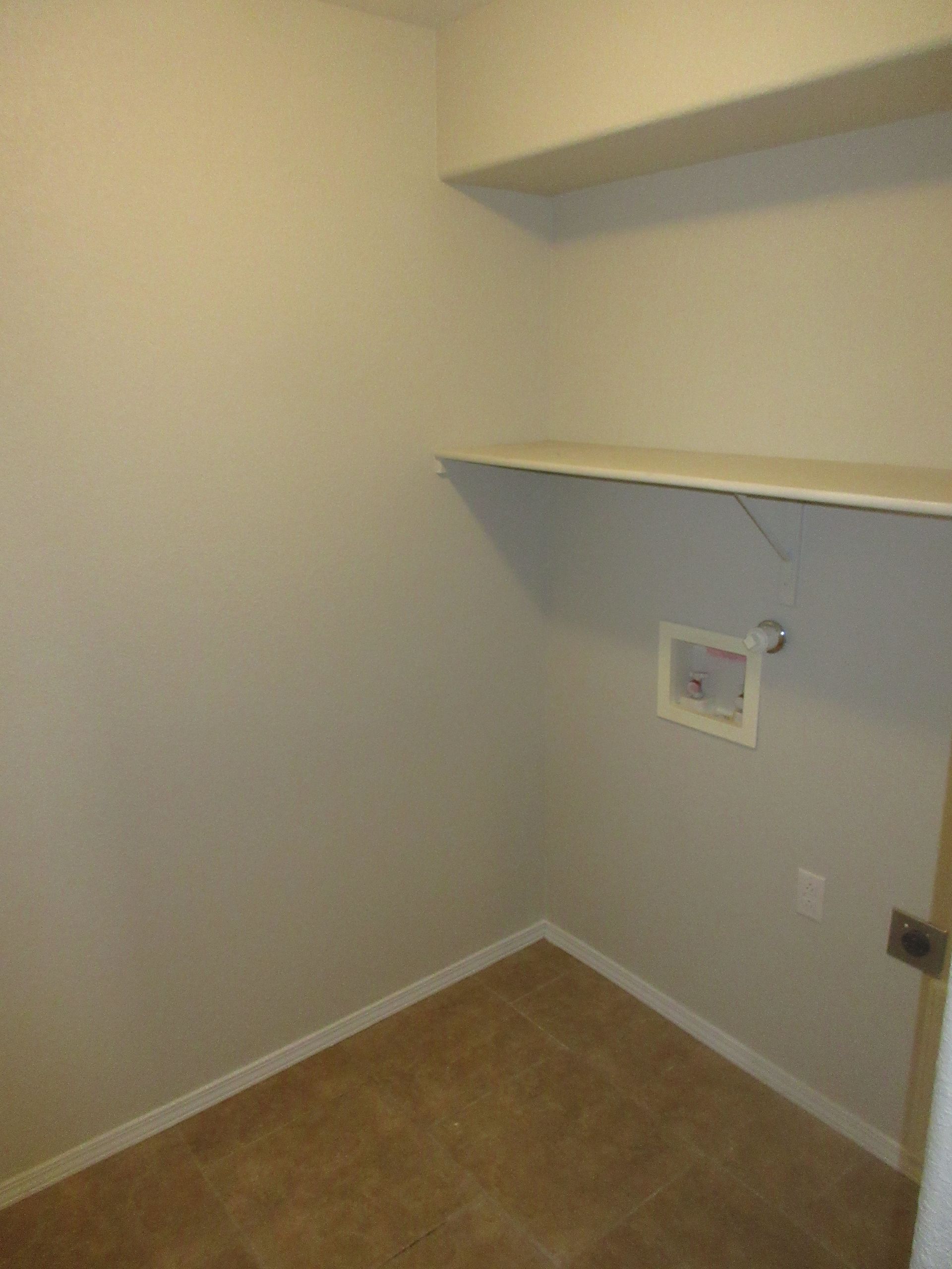 An empty closet with a shelf and a picture on the wall.