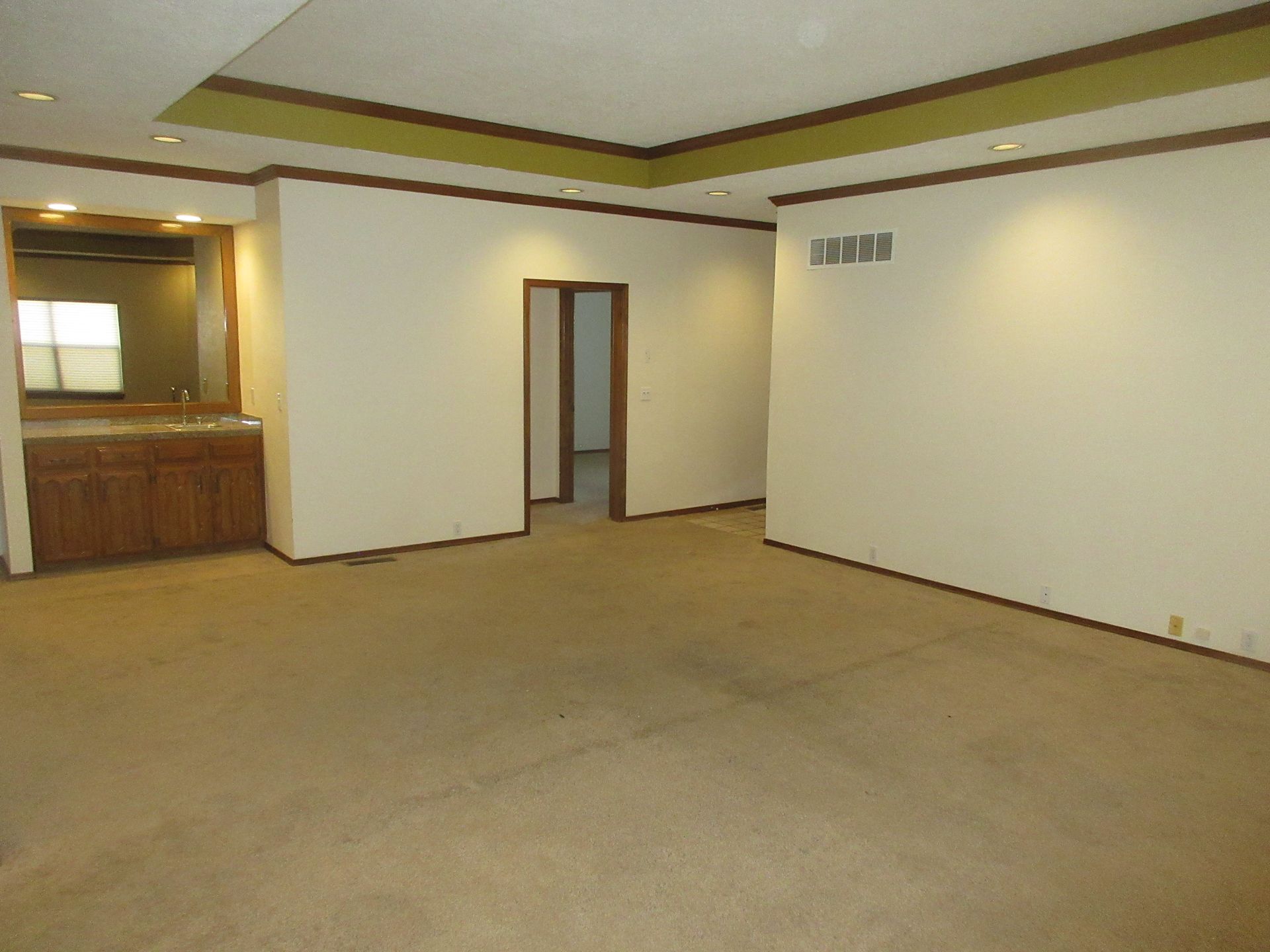 An empty living room with white walls and tan carpet