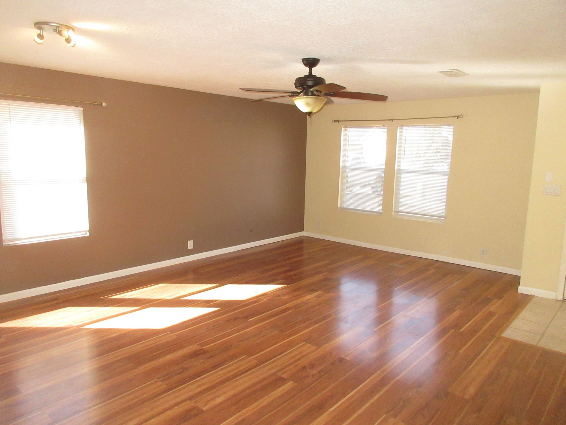 An empty living room with hardwood floors and a ceiling fan