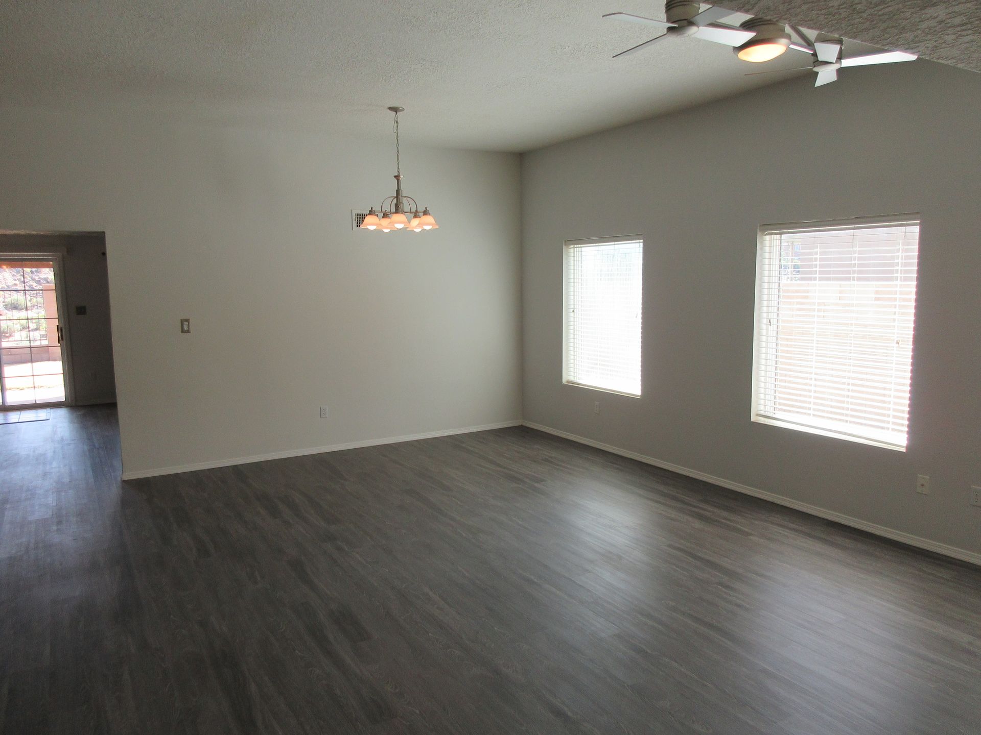 An empty living room with hardwood floors and a ceiling fan.