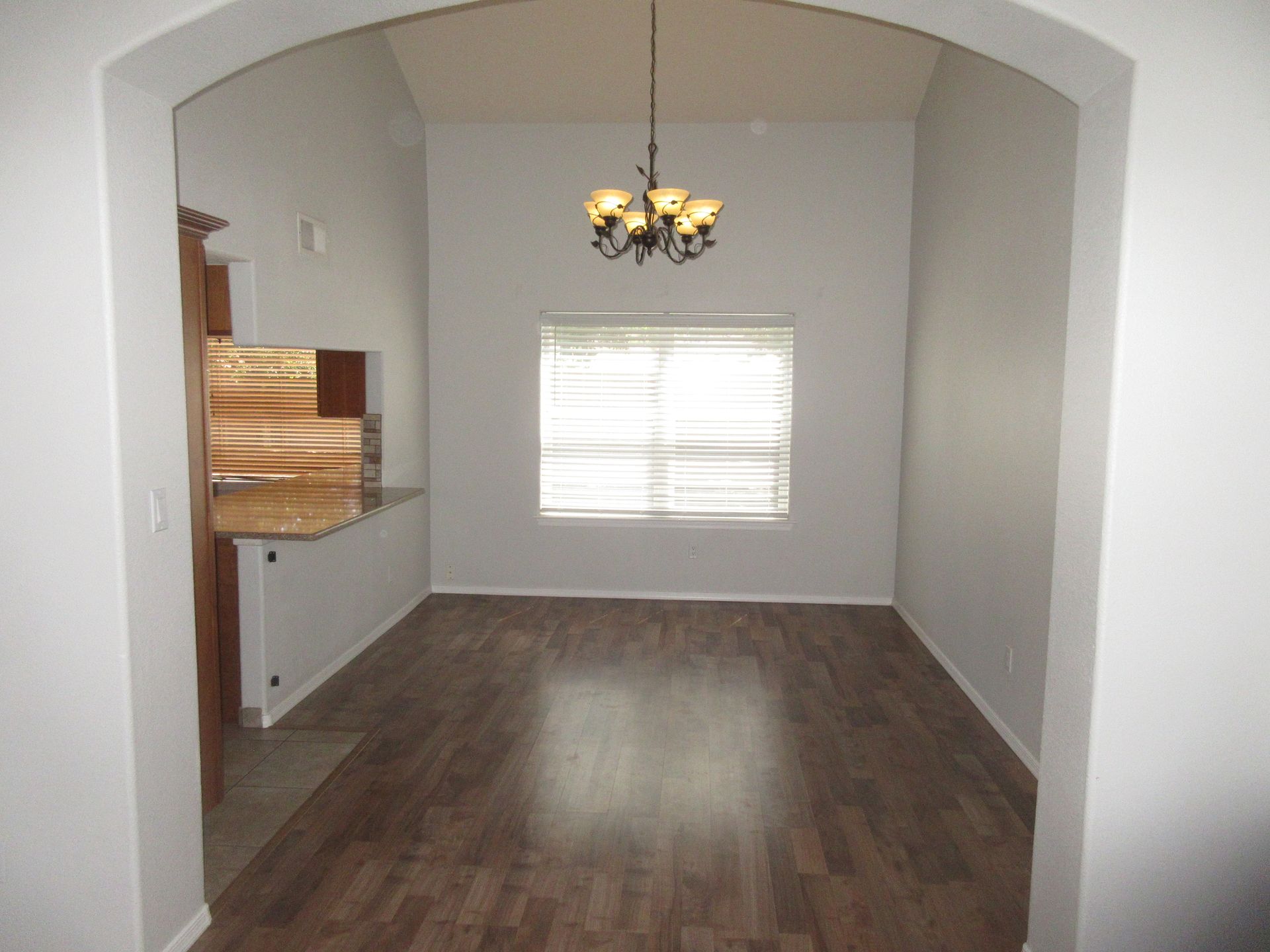 An empty dining room with a chandelier hanging from the ceiling
