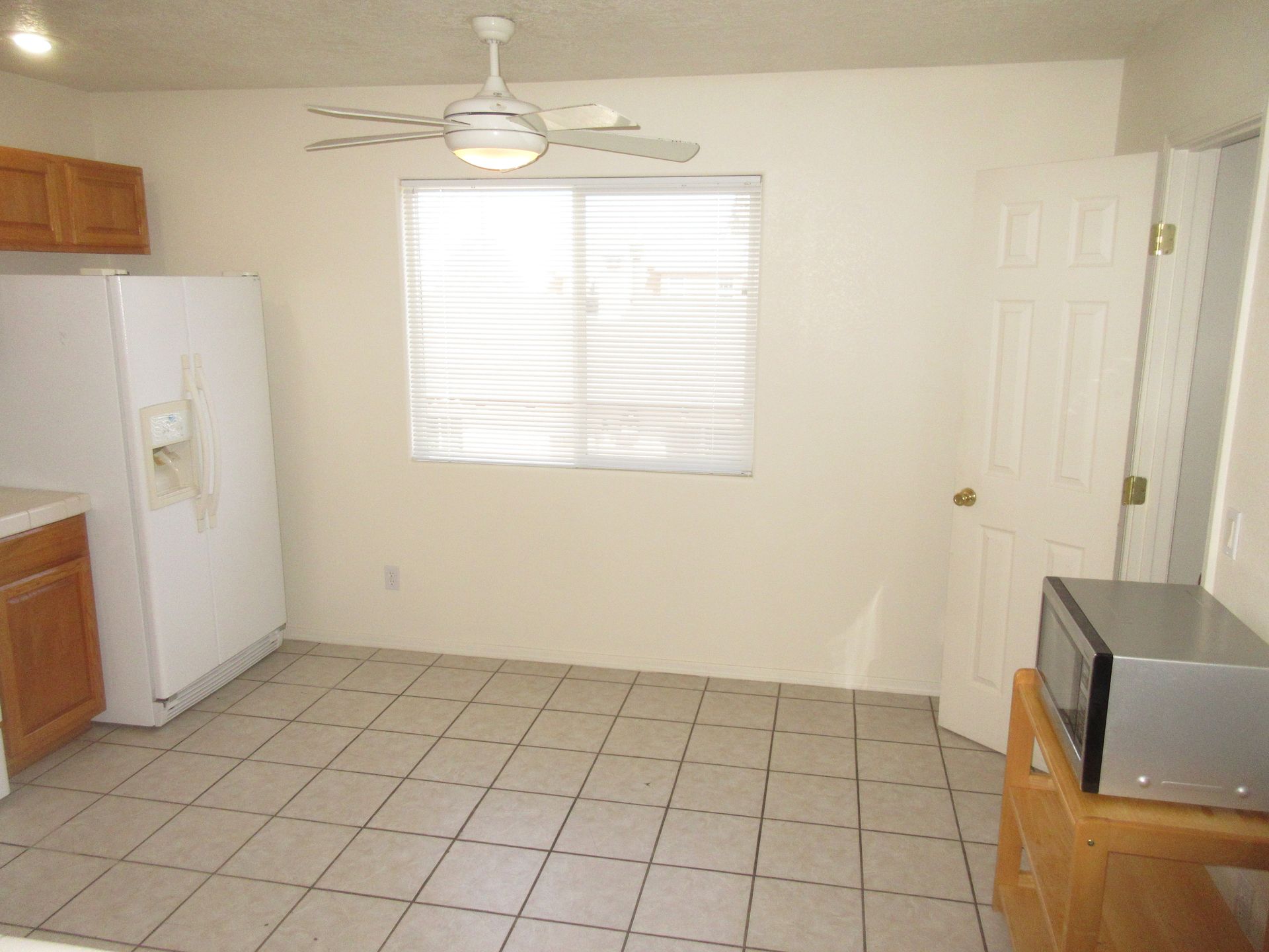A kitchen with a refrigerator a microwave and a ceiling fan
