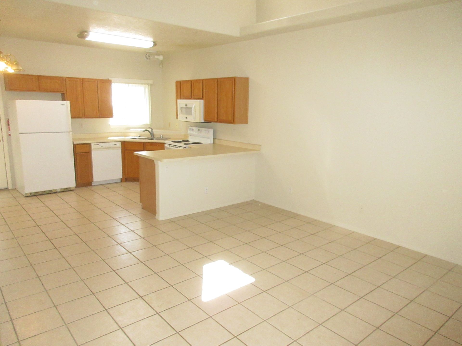 An empty kitchen with a white refrigerator and brown cabinets