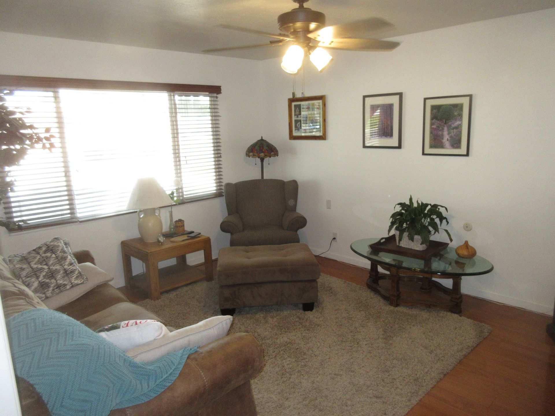 A living room with a couch a chair a table and a ceiling fan
