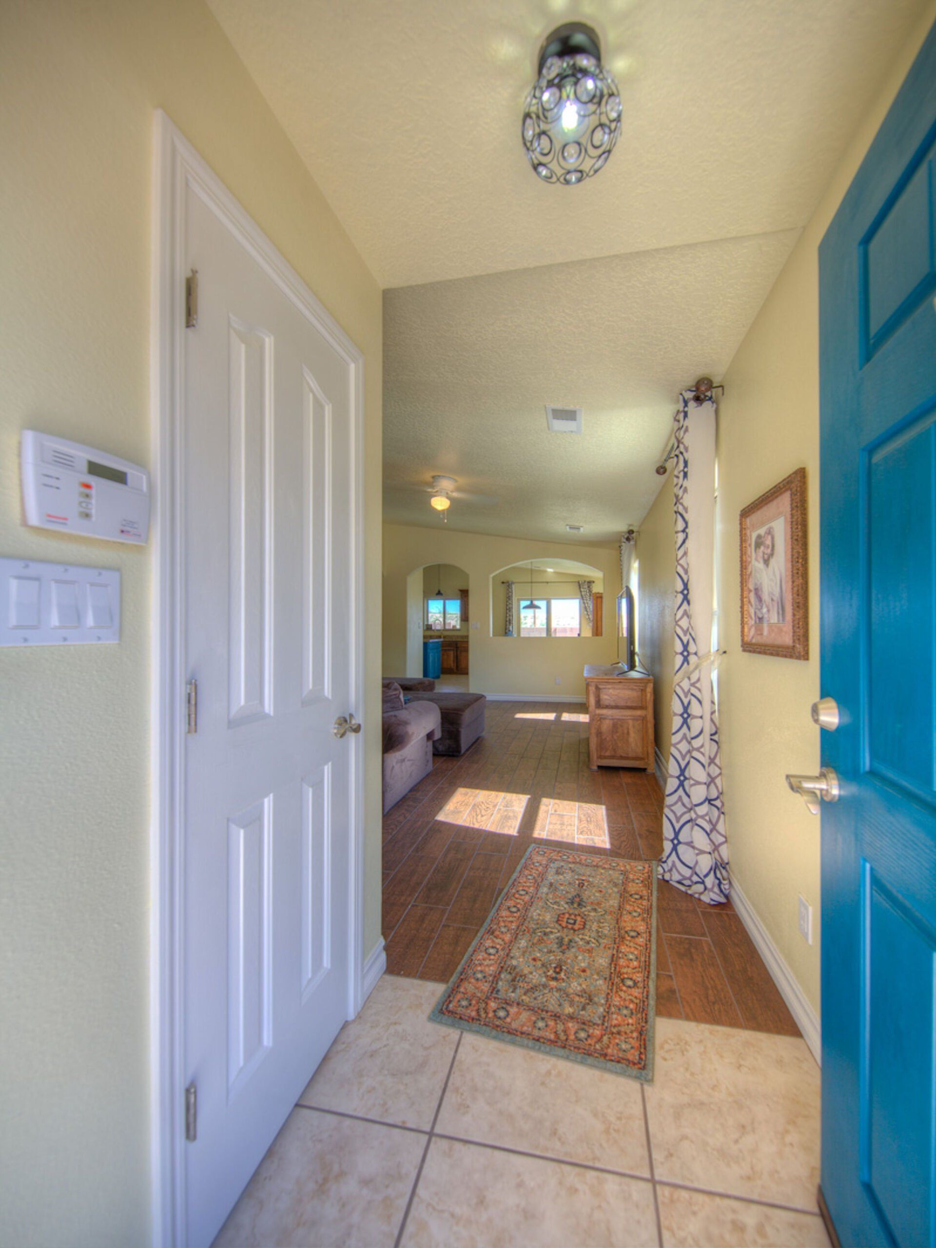 A hallway with a blue door leading to a living room