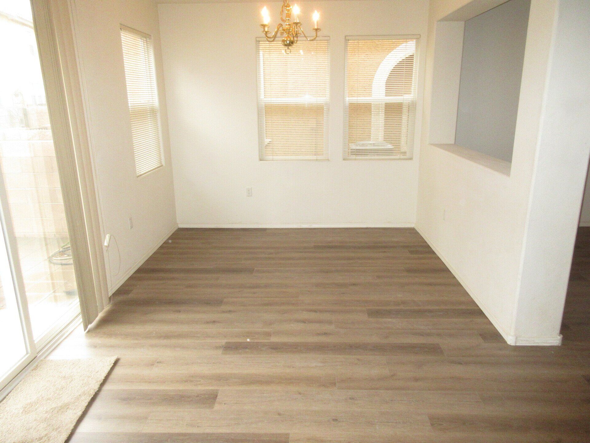 An empty dining room with hardwood floors and a chandelier