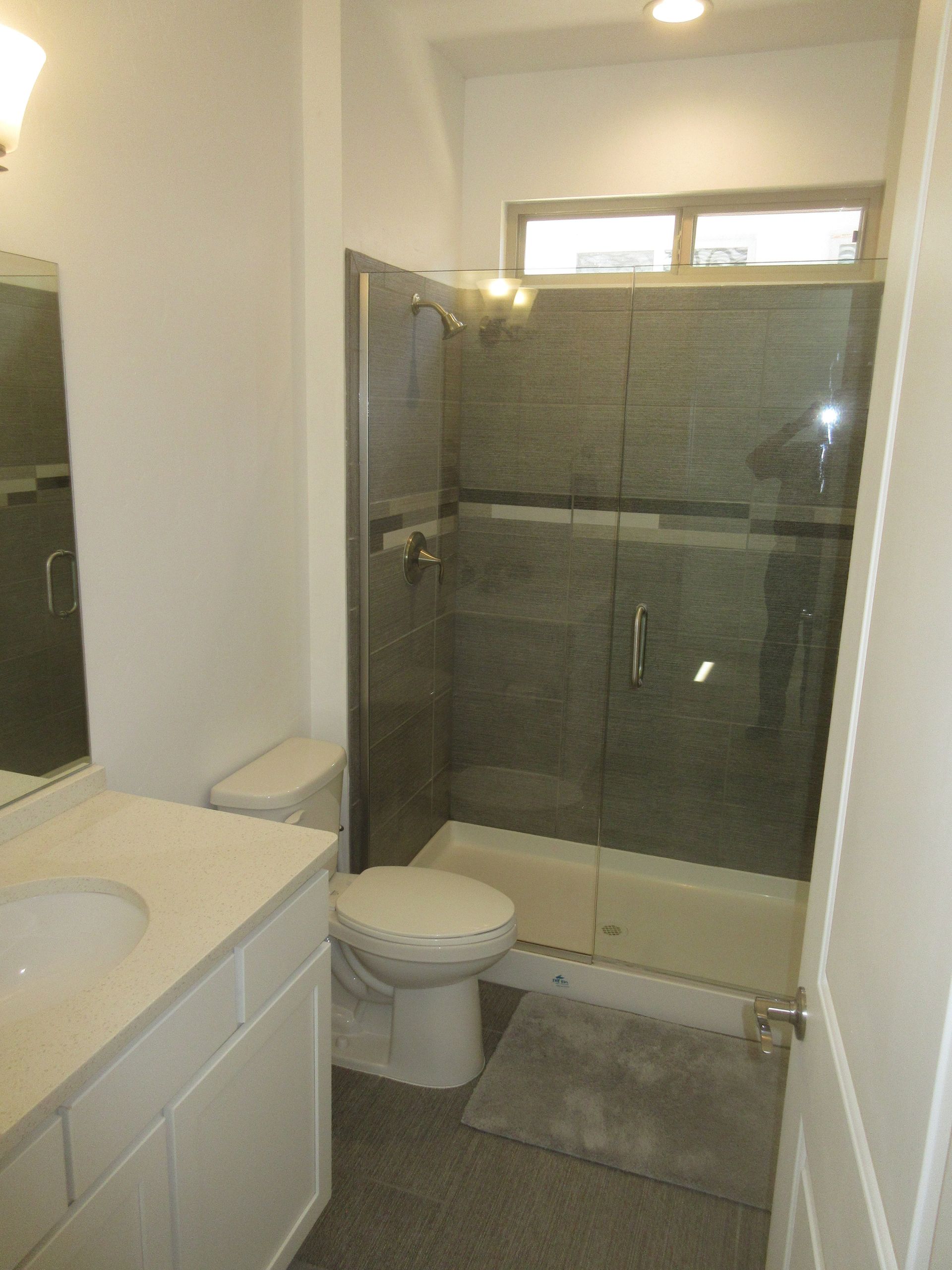 A bathroom with a toilet , sink and shower.