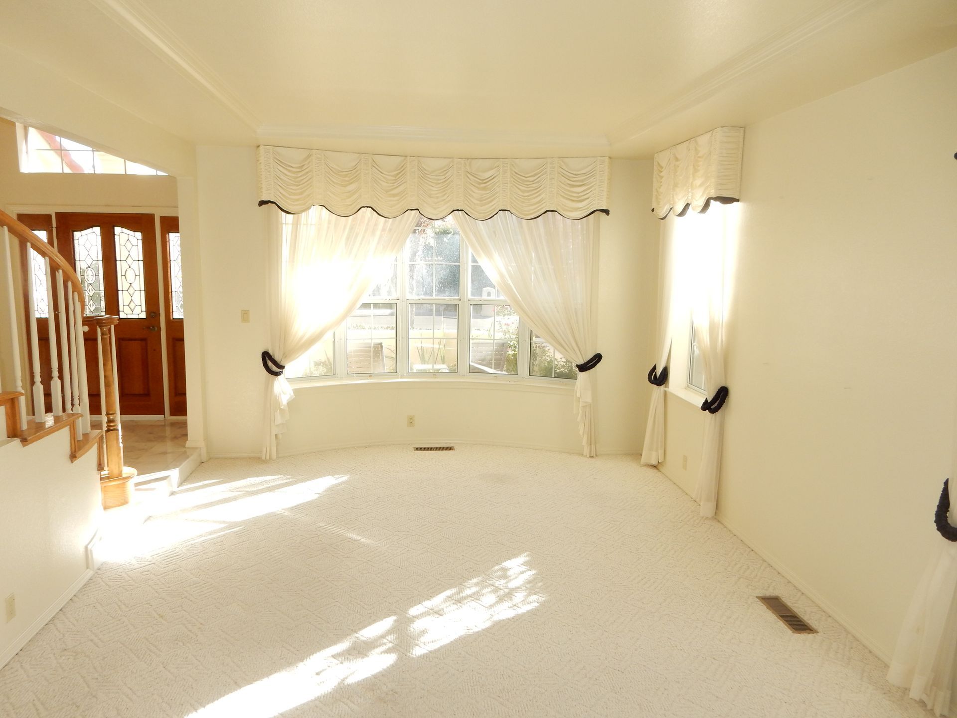 An empty living room with white carpet and white curtains