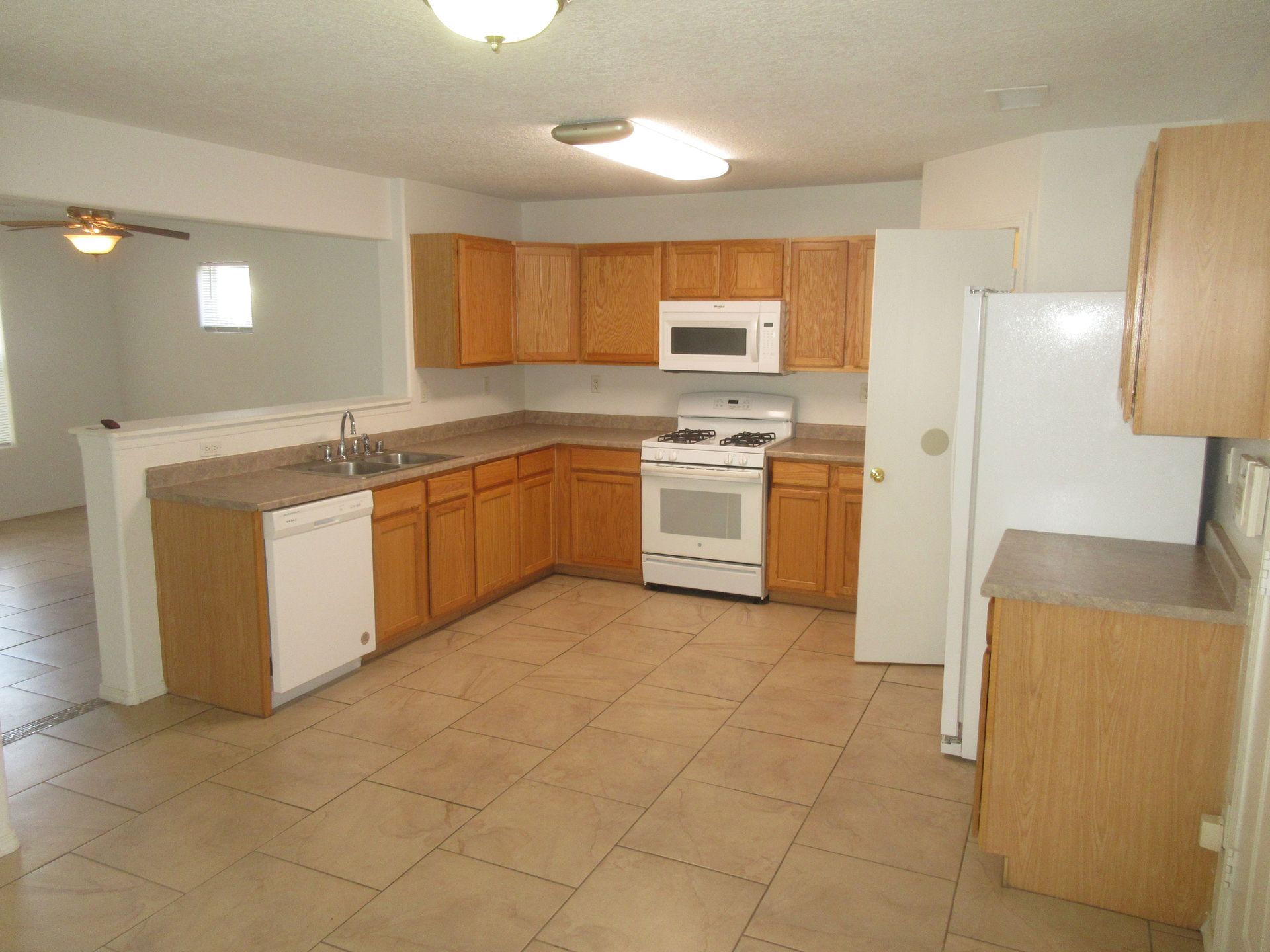 An empty kitchen with wooden cabinets and a white refrigerator