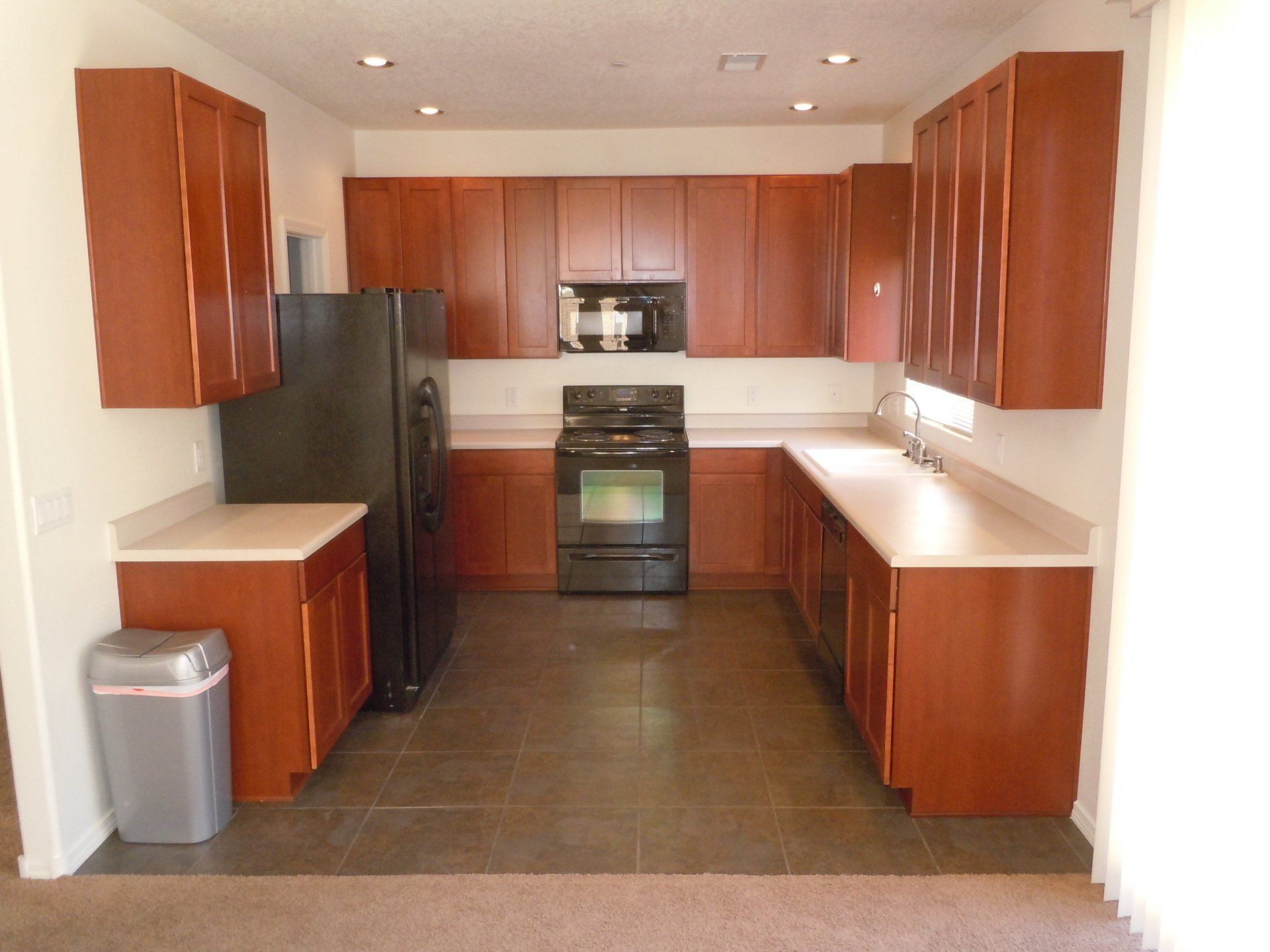 A kitchen with wooden cabinets and a black refrigerator