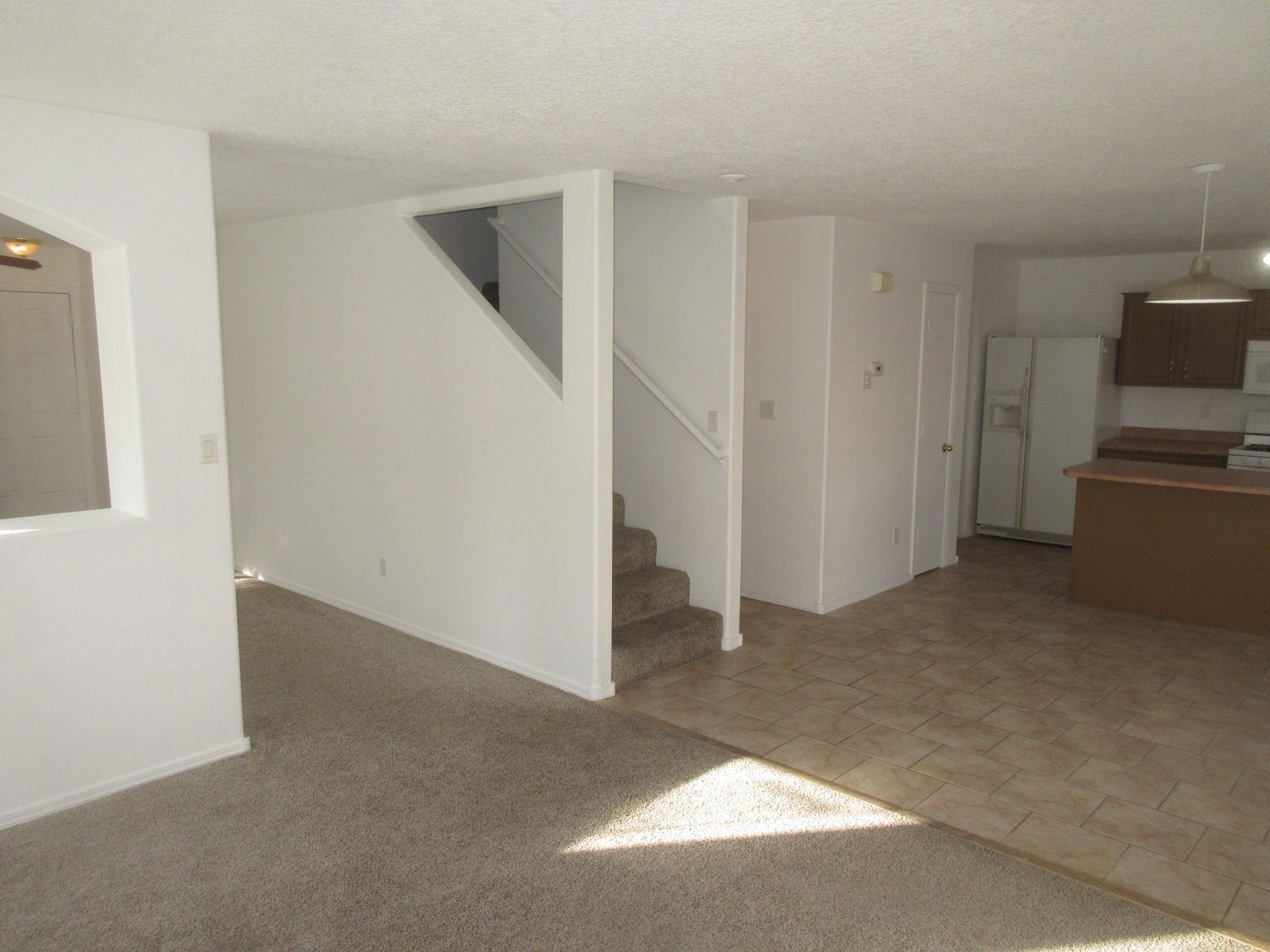 A living room with stairs leading up to the second floor and a kitchen.