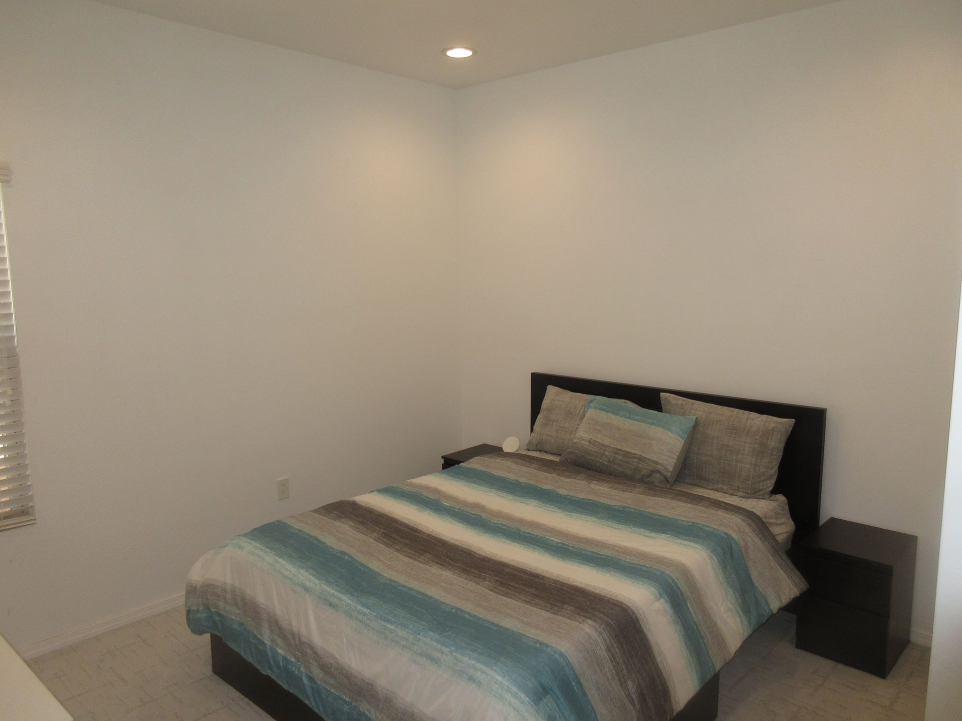 A bedroom with a bed , nightstand and window