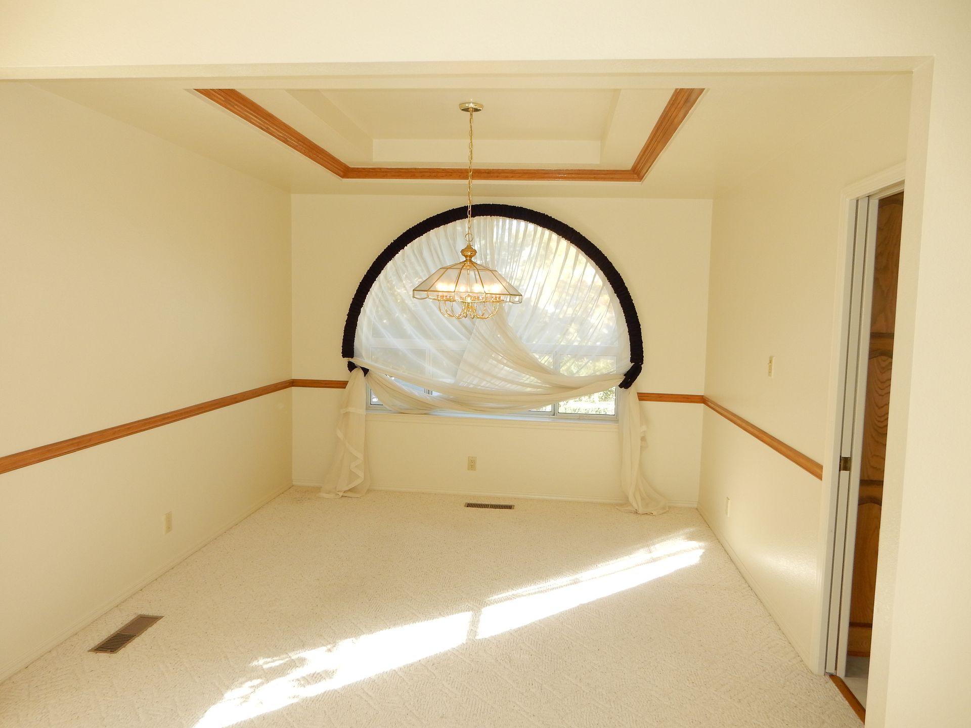 An empty dining room with a chandelier hanging from the ceiling
