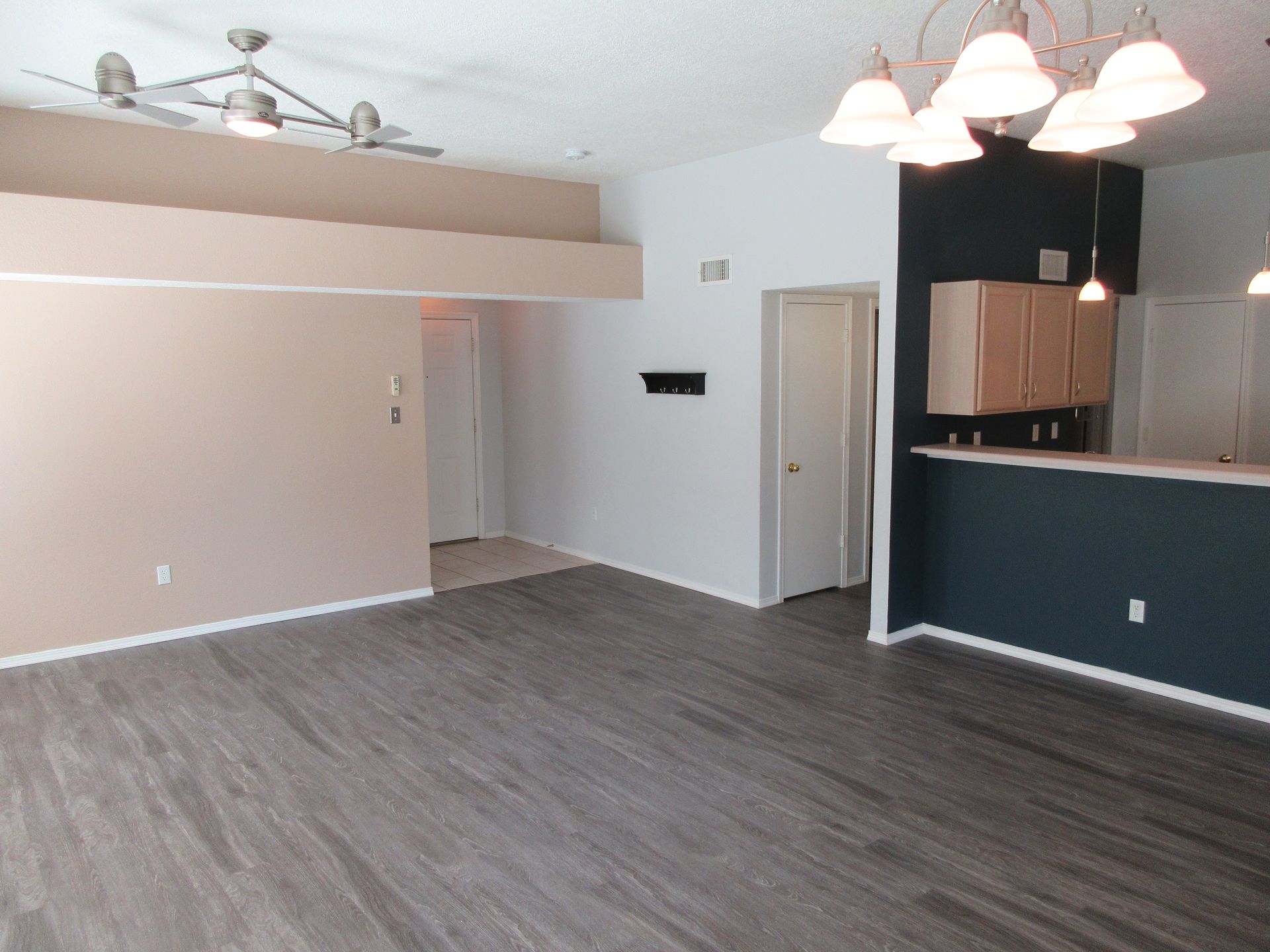 An empty living room with hardwood floors and a ceiling fan