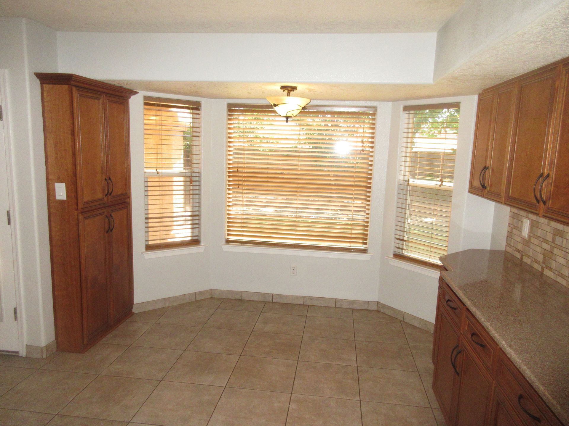 A kitchen with wooden cabinets and a window with blinds