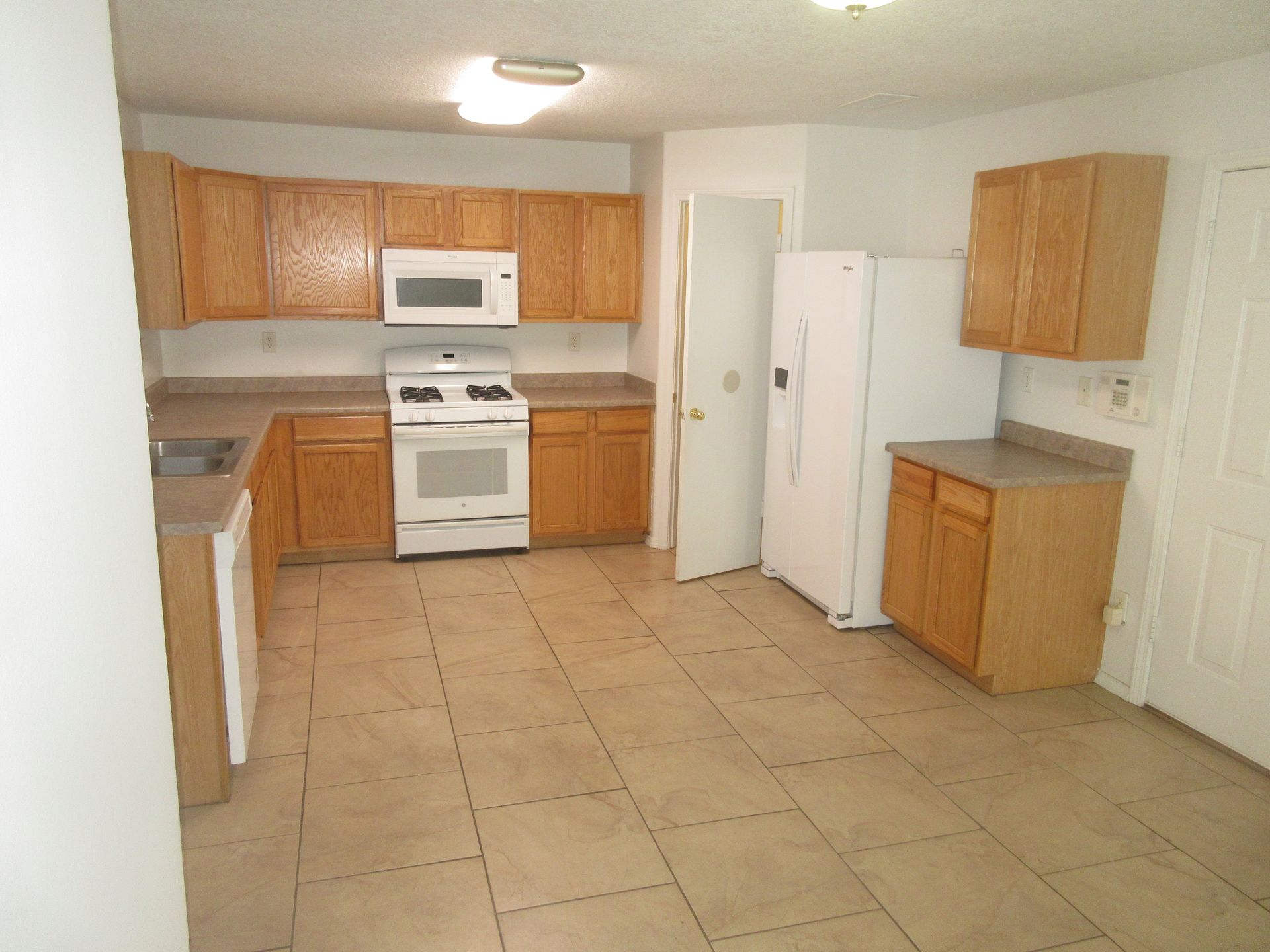 An empty kitchen with wooden cabinets and a white refrigerator