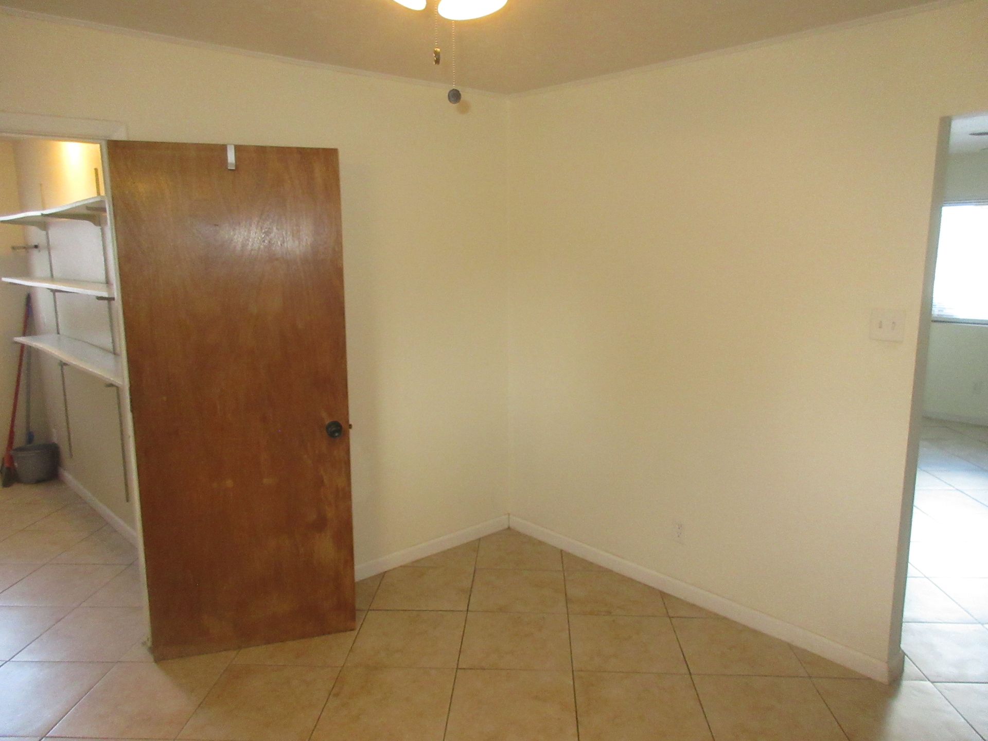 An empty room with a wooden door and shelves.