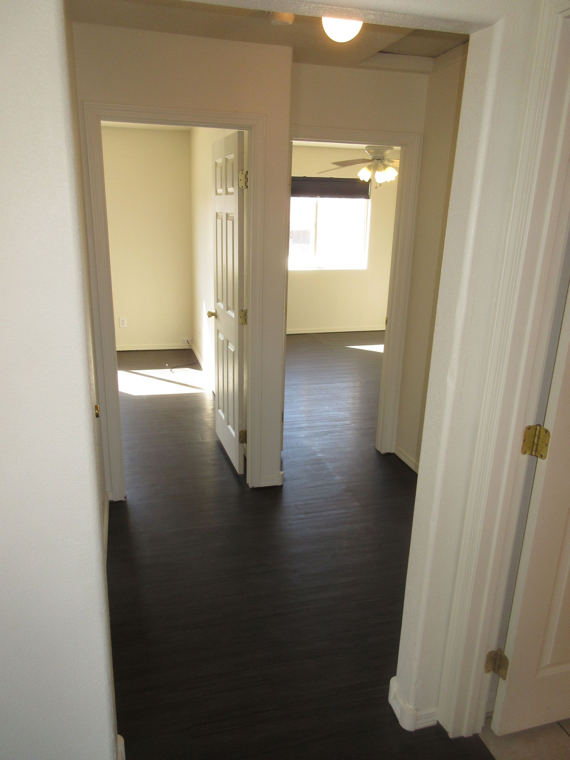 A hallway leading to a bedroom with a ceiling fan