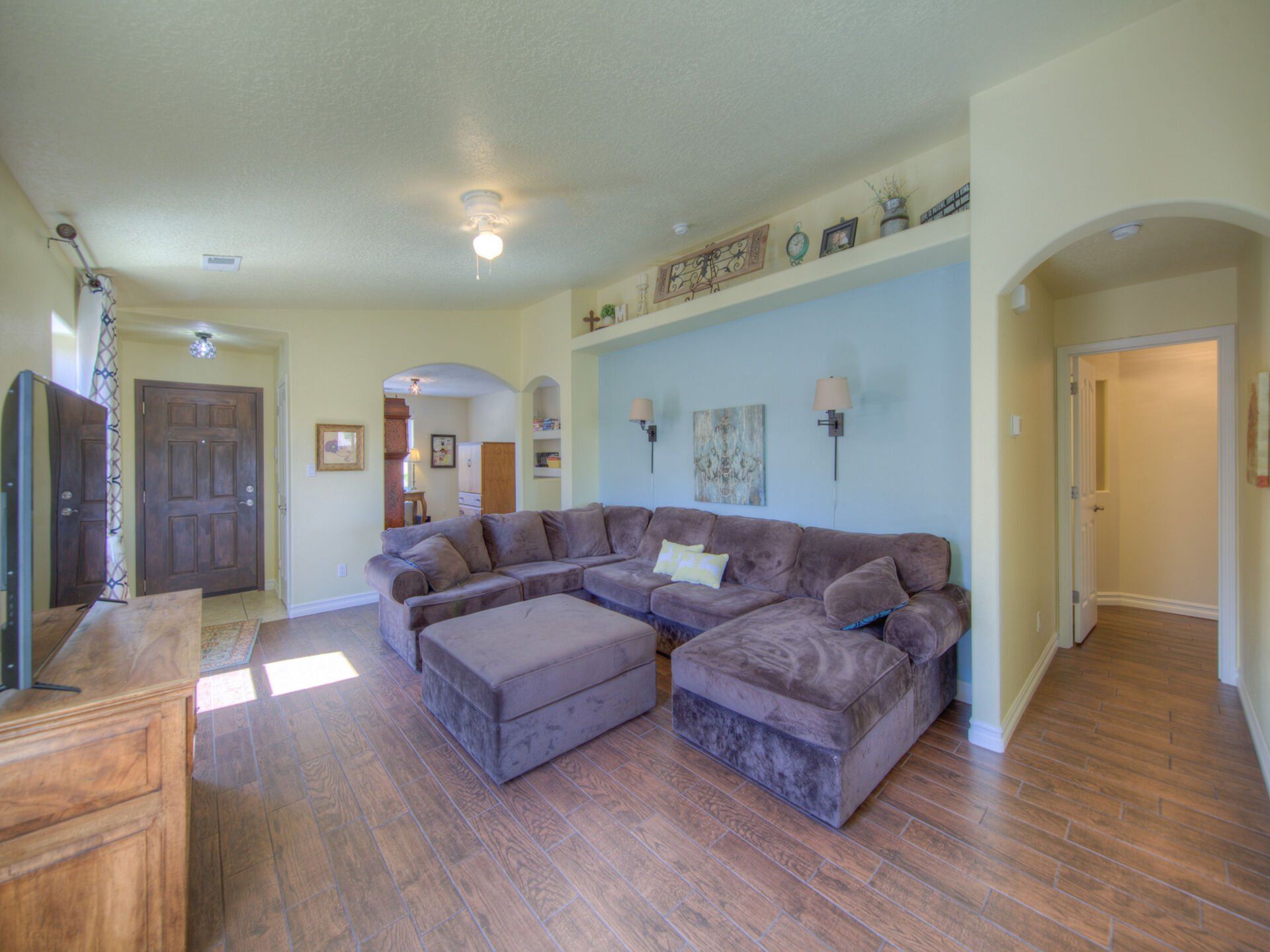 A living room with a large sectional couch , ottoman , and television.