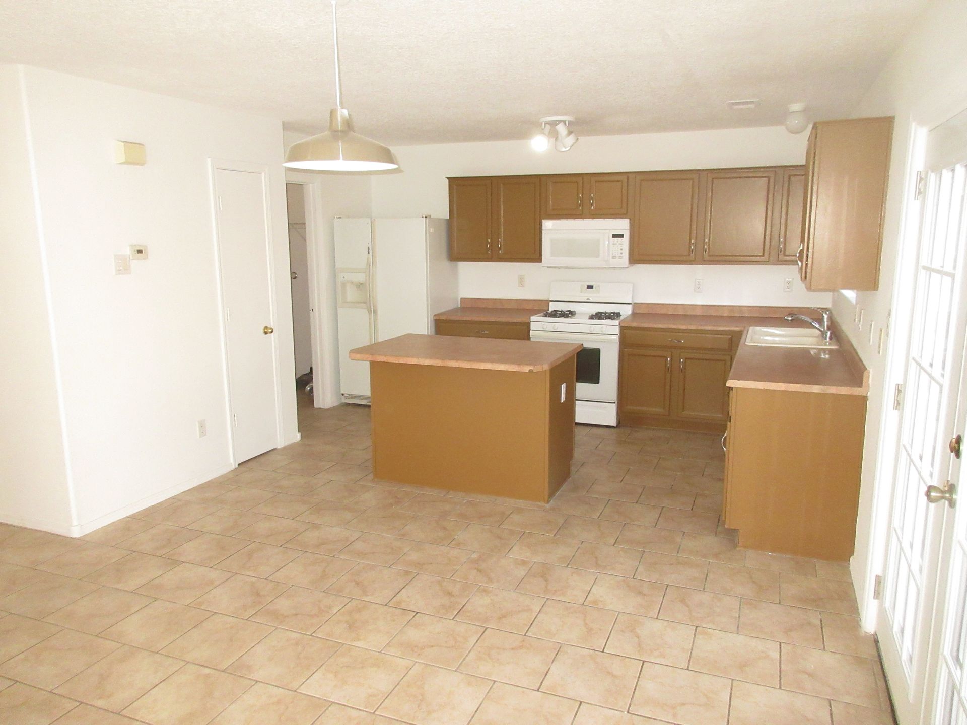 An empty kitchen with brown cabinets and a white stove