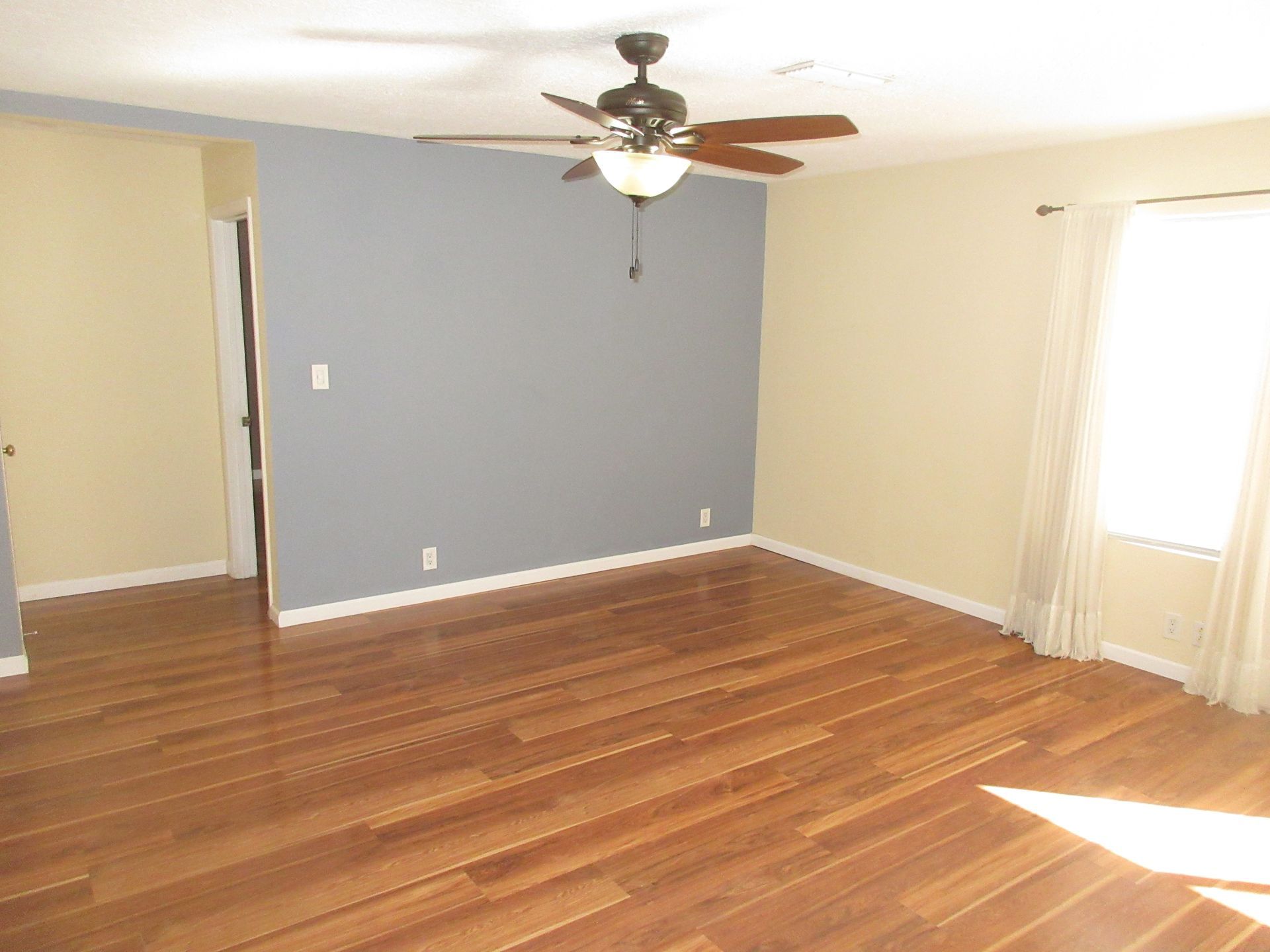 A living room with hardwood floors and a ceiling fan