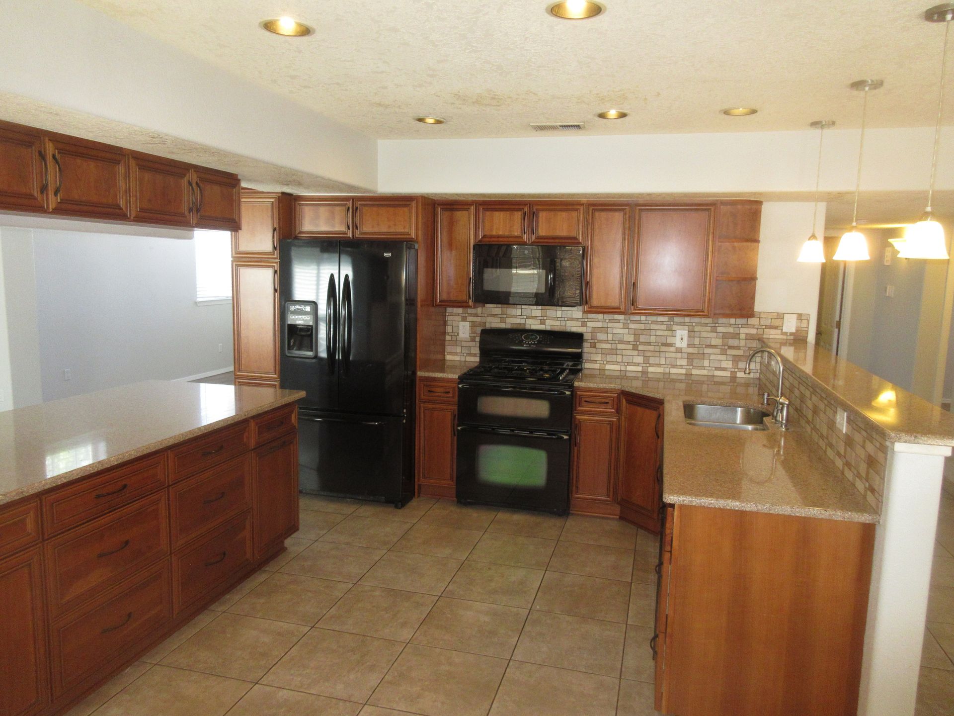 A kitchen with wooden cabinets and a black refrigerator