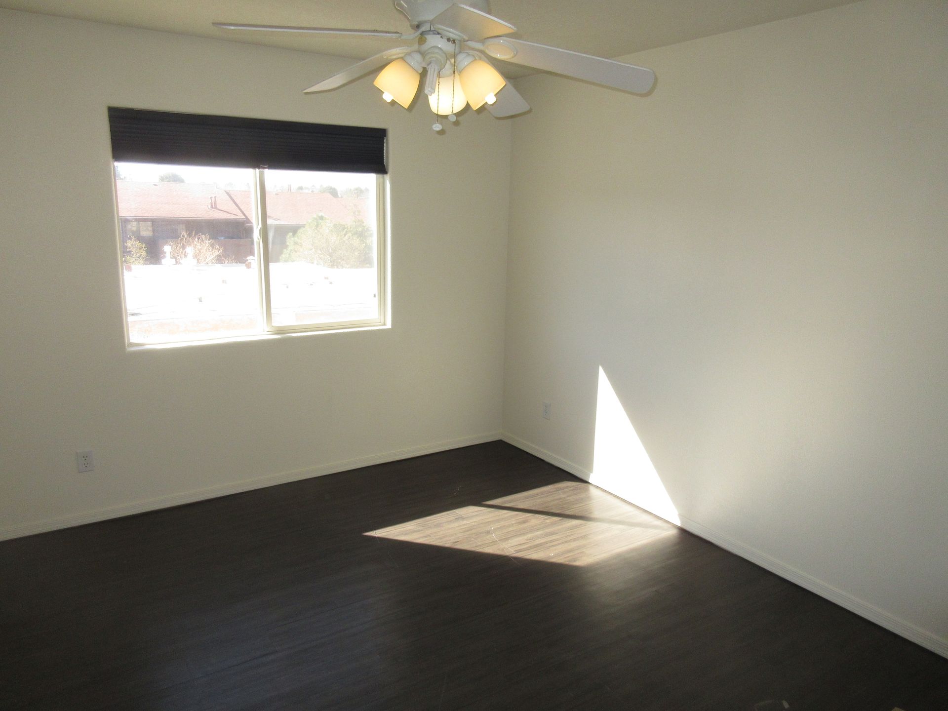 An empty room with a ceiling fan and a window