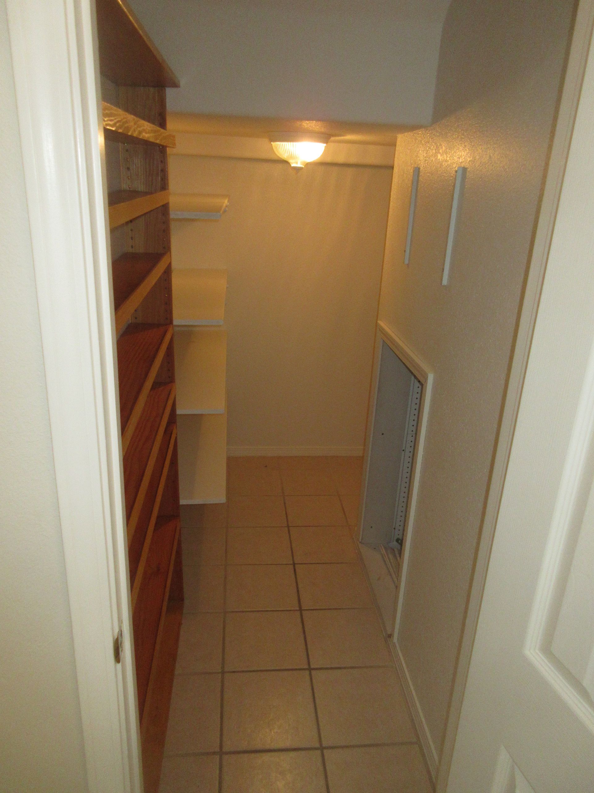 A walk in closet with lots of shelves and a fireplace.