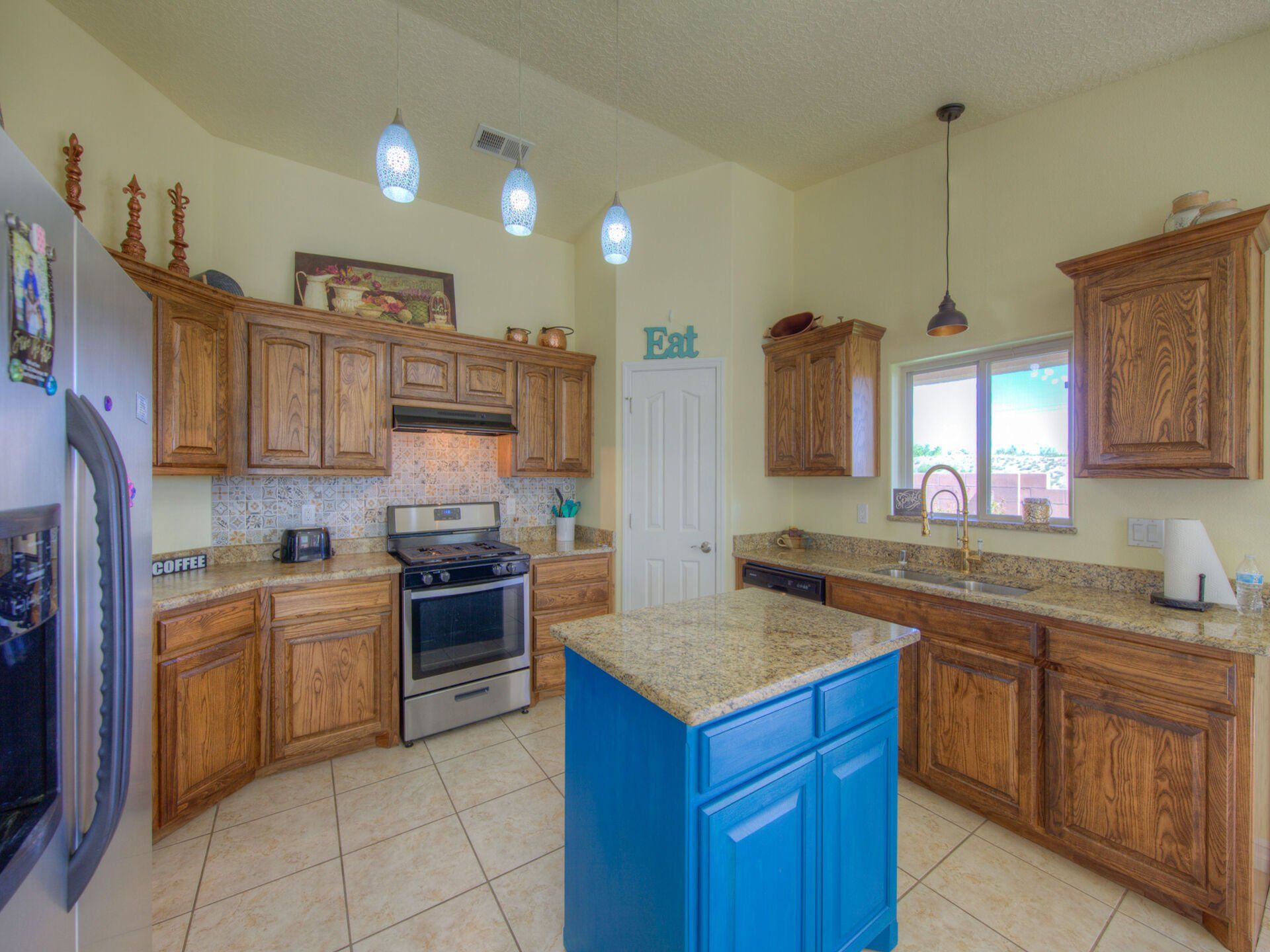 A kitchen with wooden cabinets and a blue island.