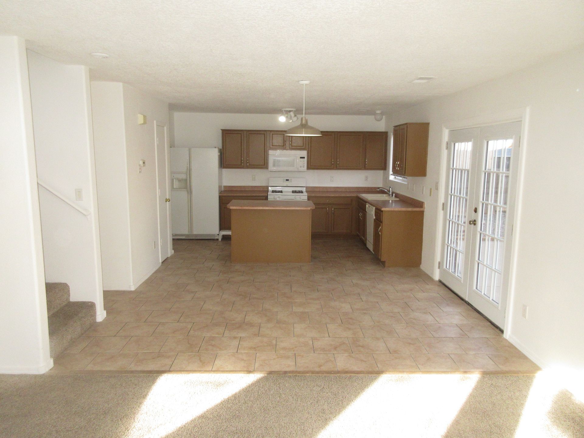 An empty kitchen with brown cabinets and white appliances